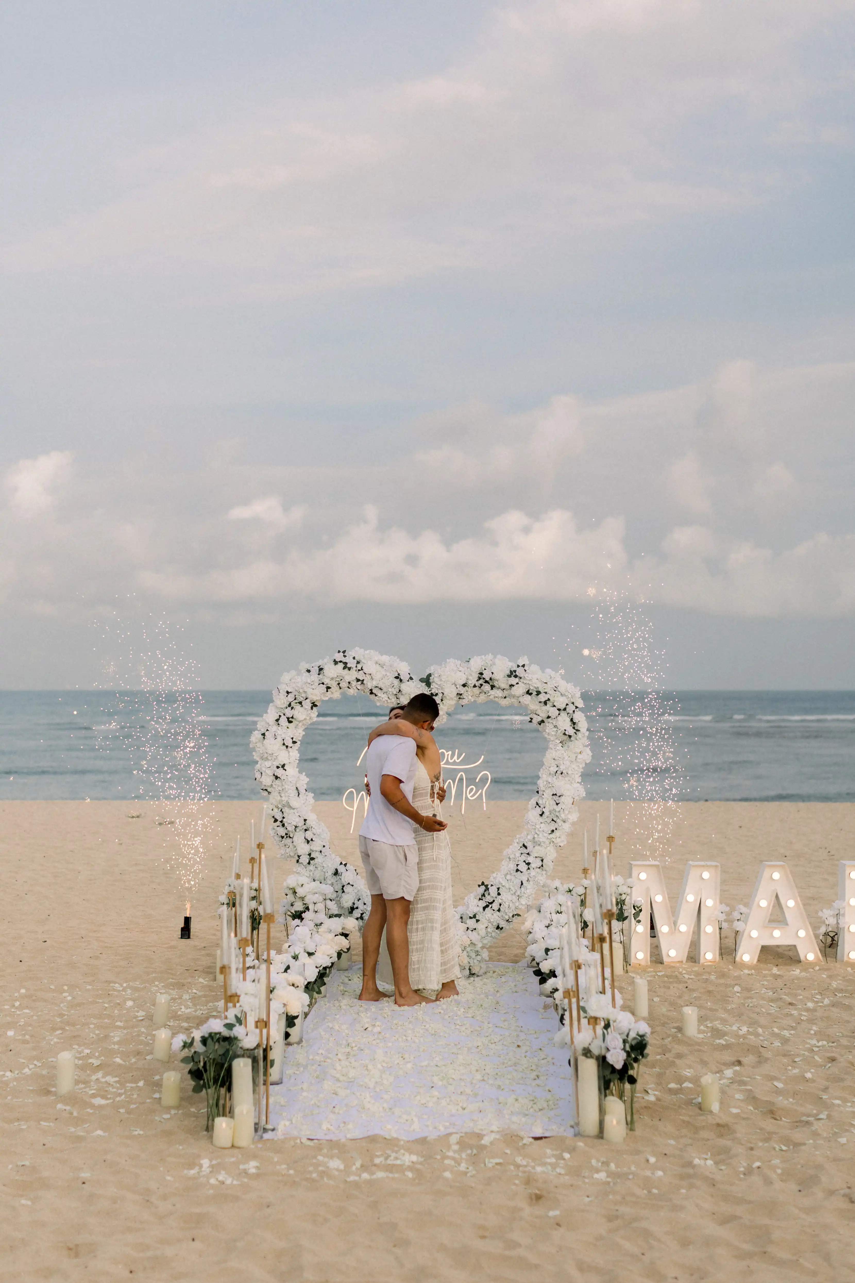 Emotional proposal moment with fireworks on a Bali beach.
