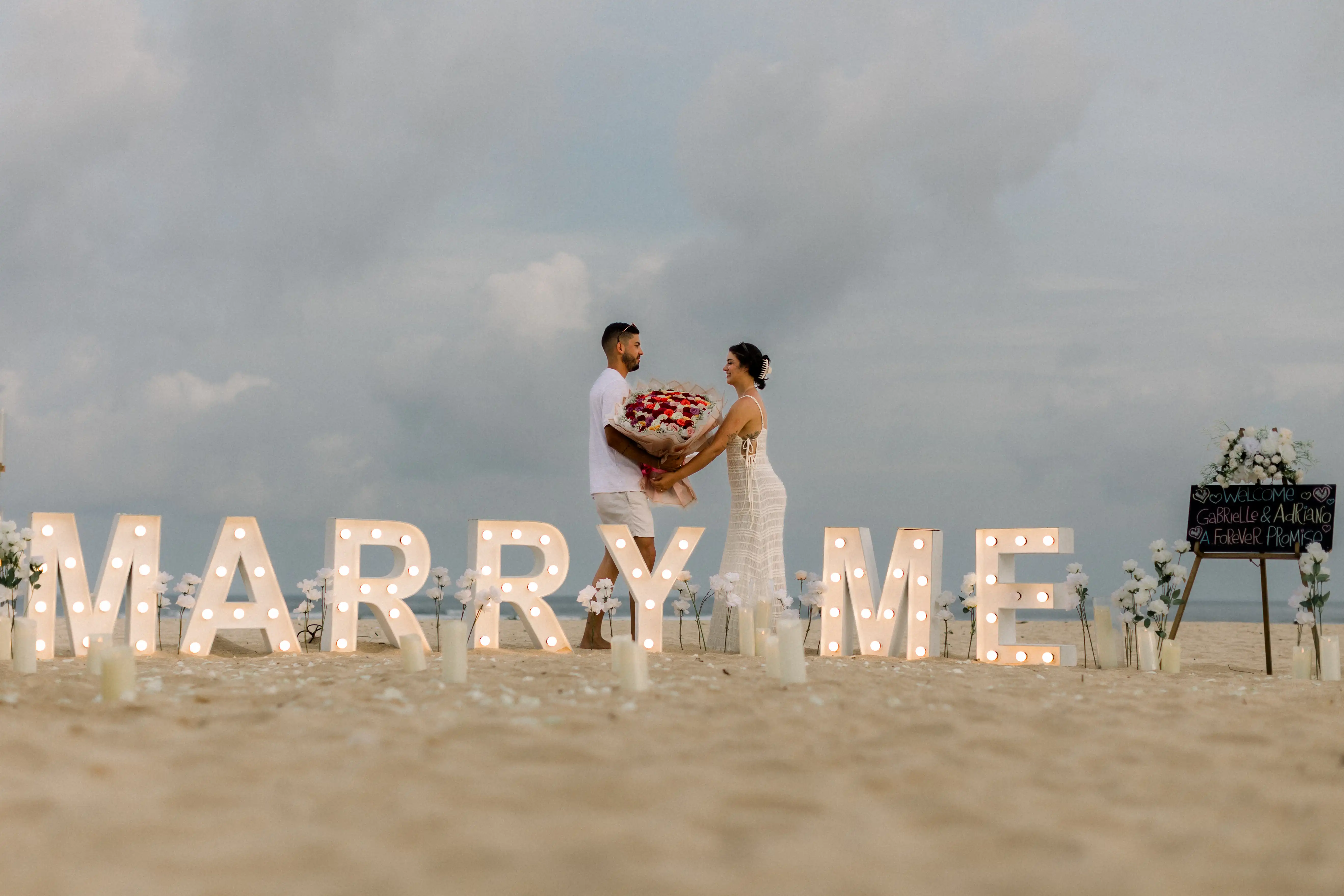 “Marry Me” light-up letters and fireworks at Bali beach proposal setup.