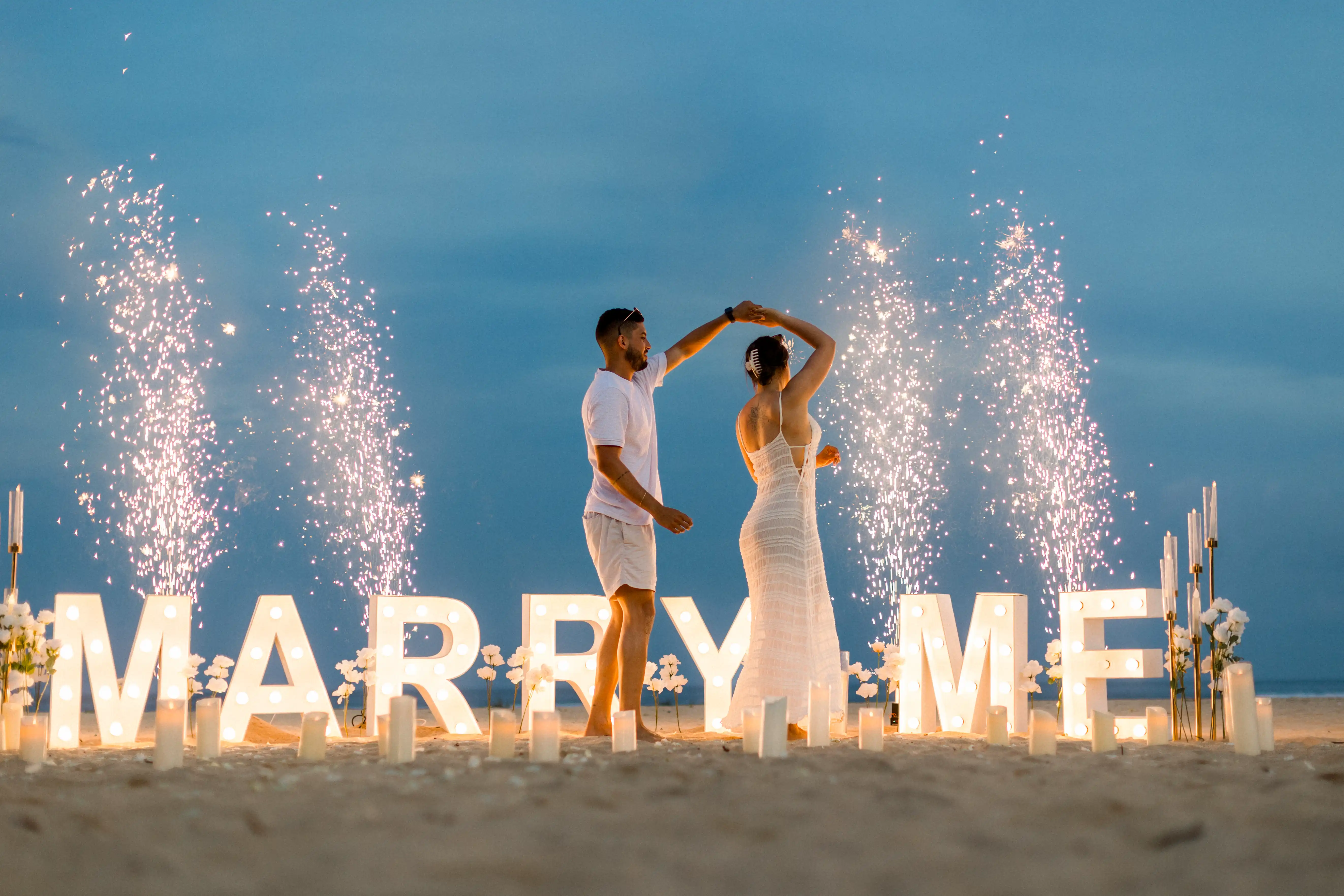 Surprise beach proposal in Bali with fireworks and glowing “Marry Me” display.