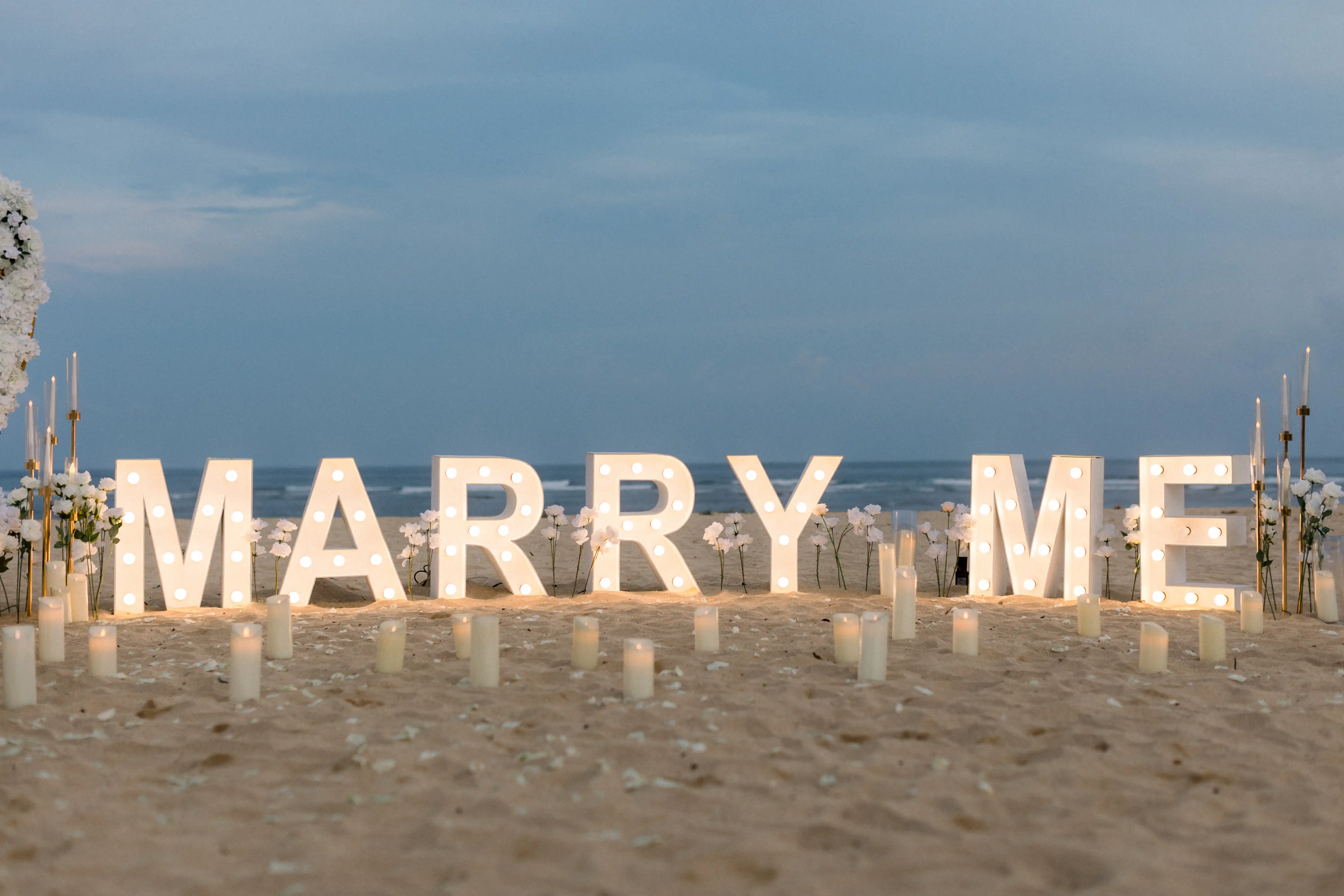 Bali beach engagement under the stars with white floral decor and ocean view.