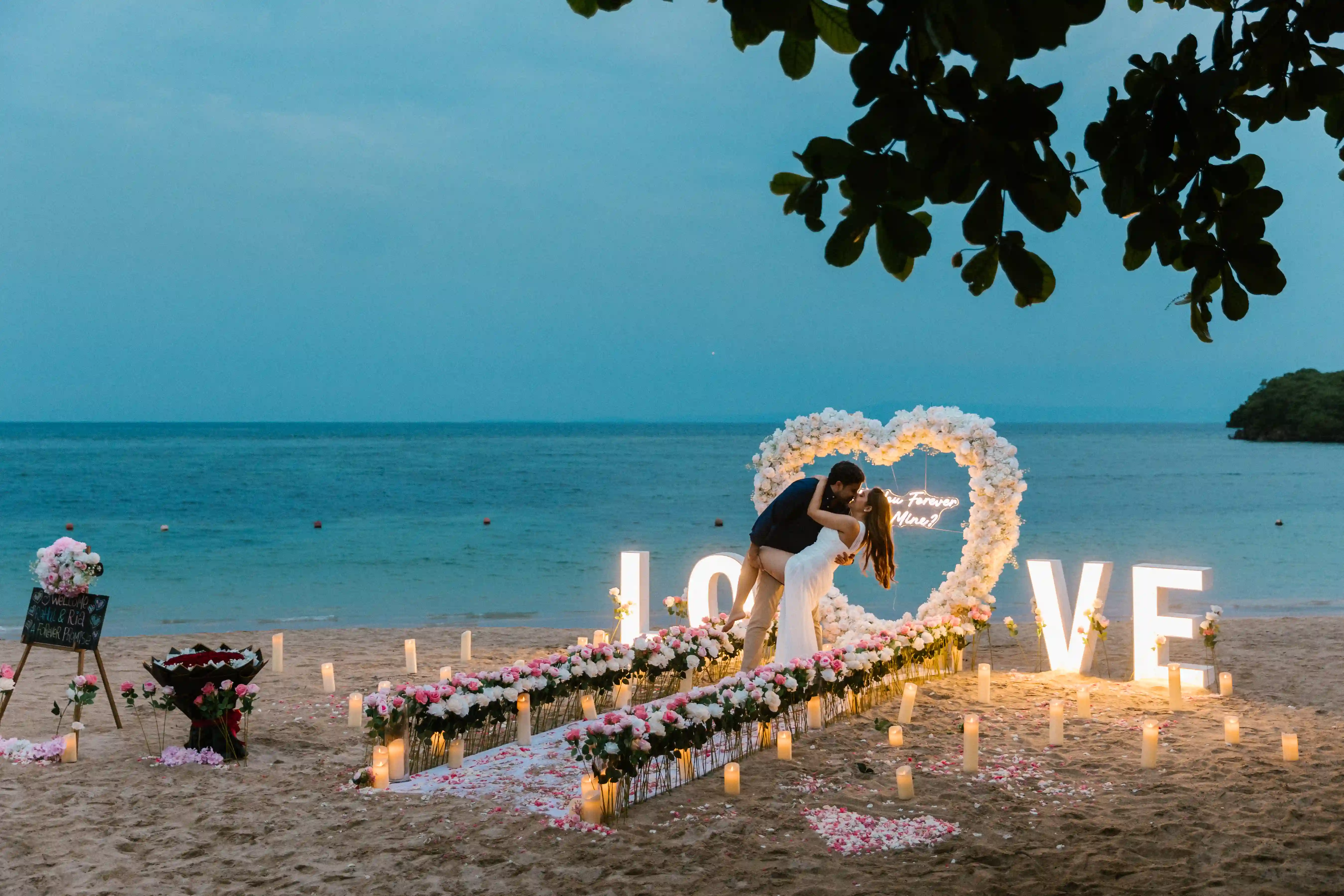 Sunset luxury beach proposal setup with illuminated LOVE letters and ocean view