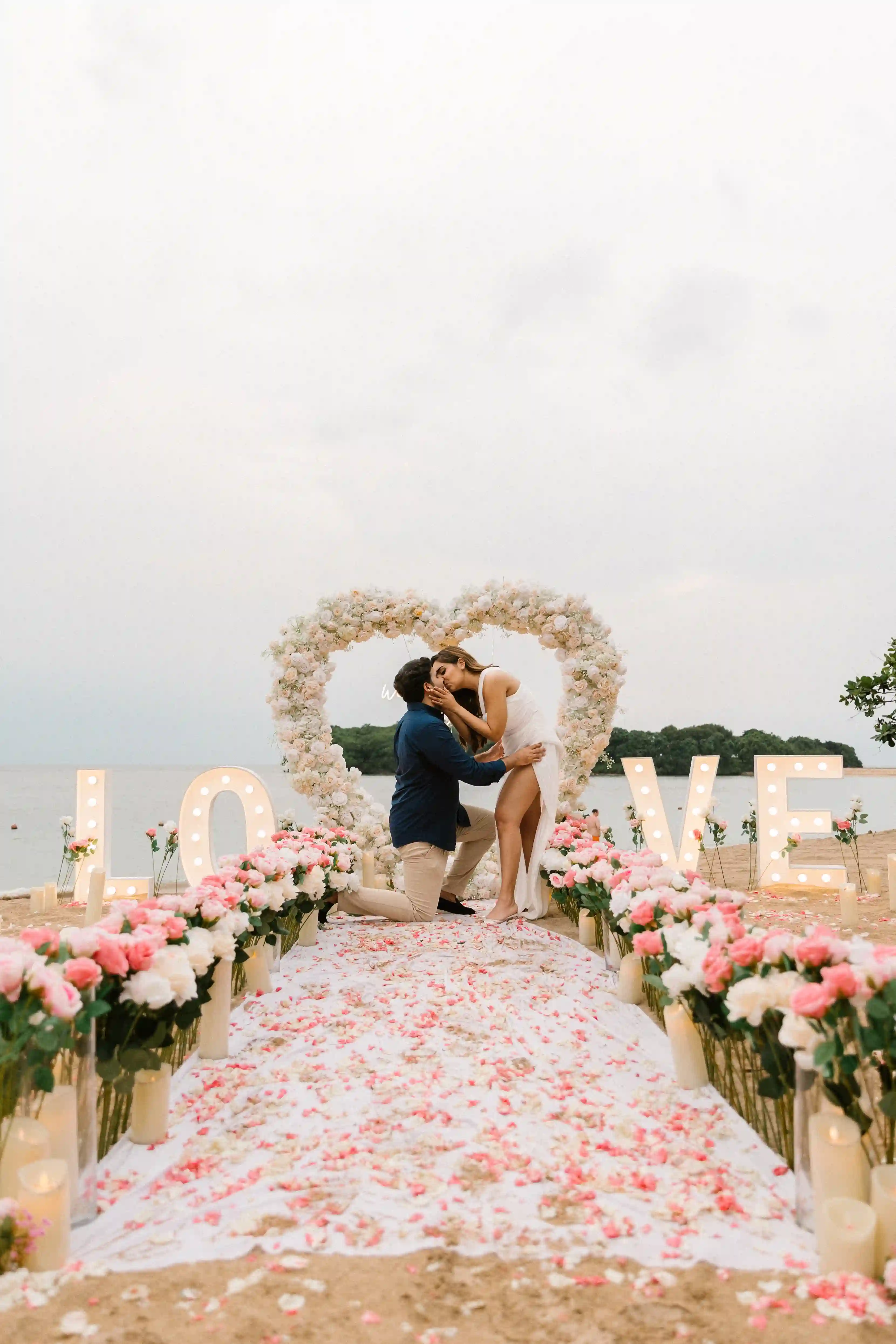Luxury beach proposal setup with floral heart arch and rose-lined aisle in Bali