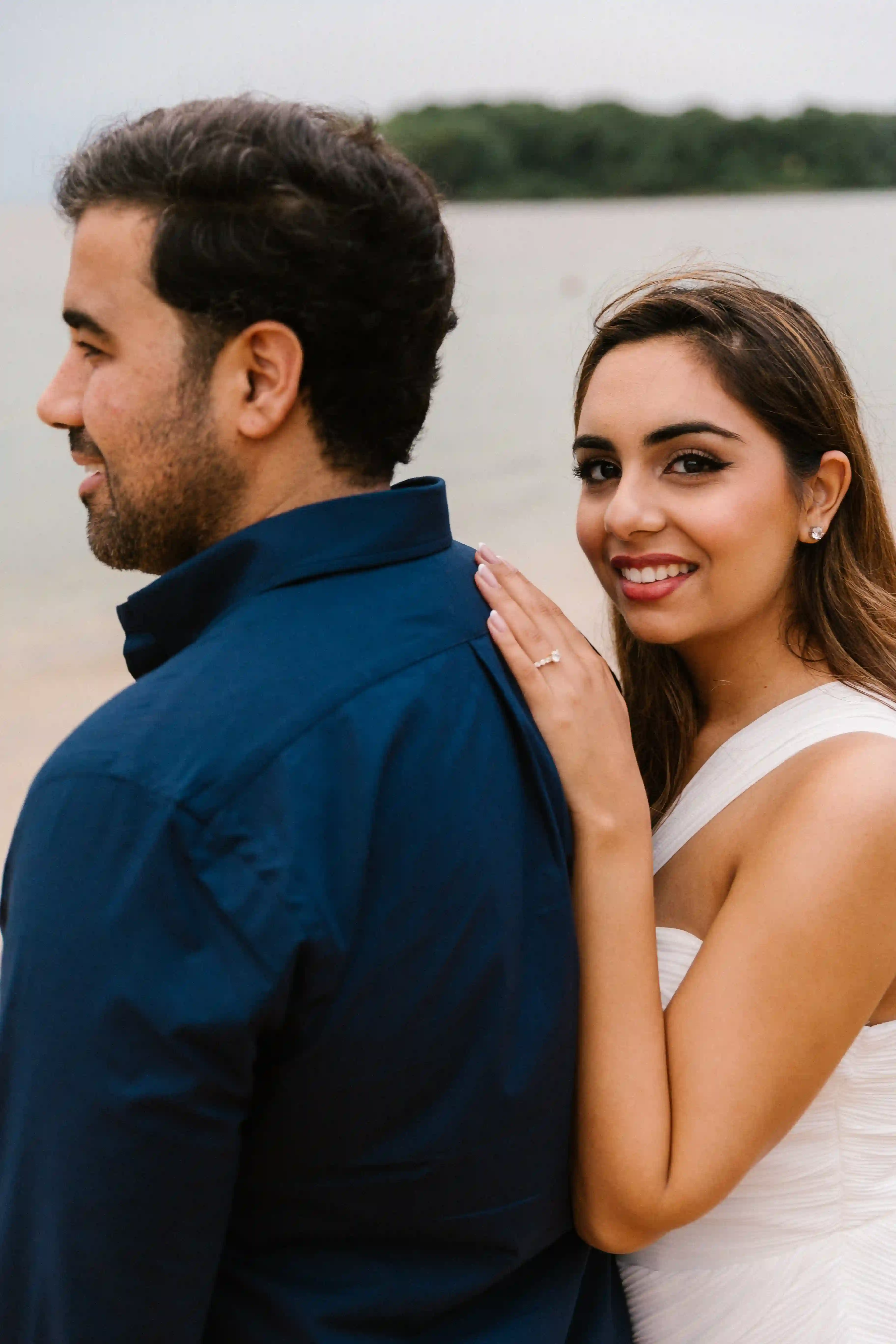Engaged couple posing together during a luxury beach proposal photoshoot
