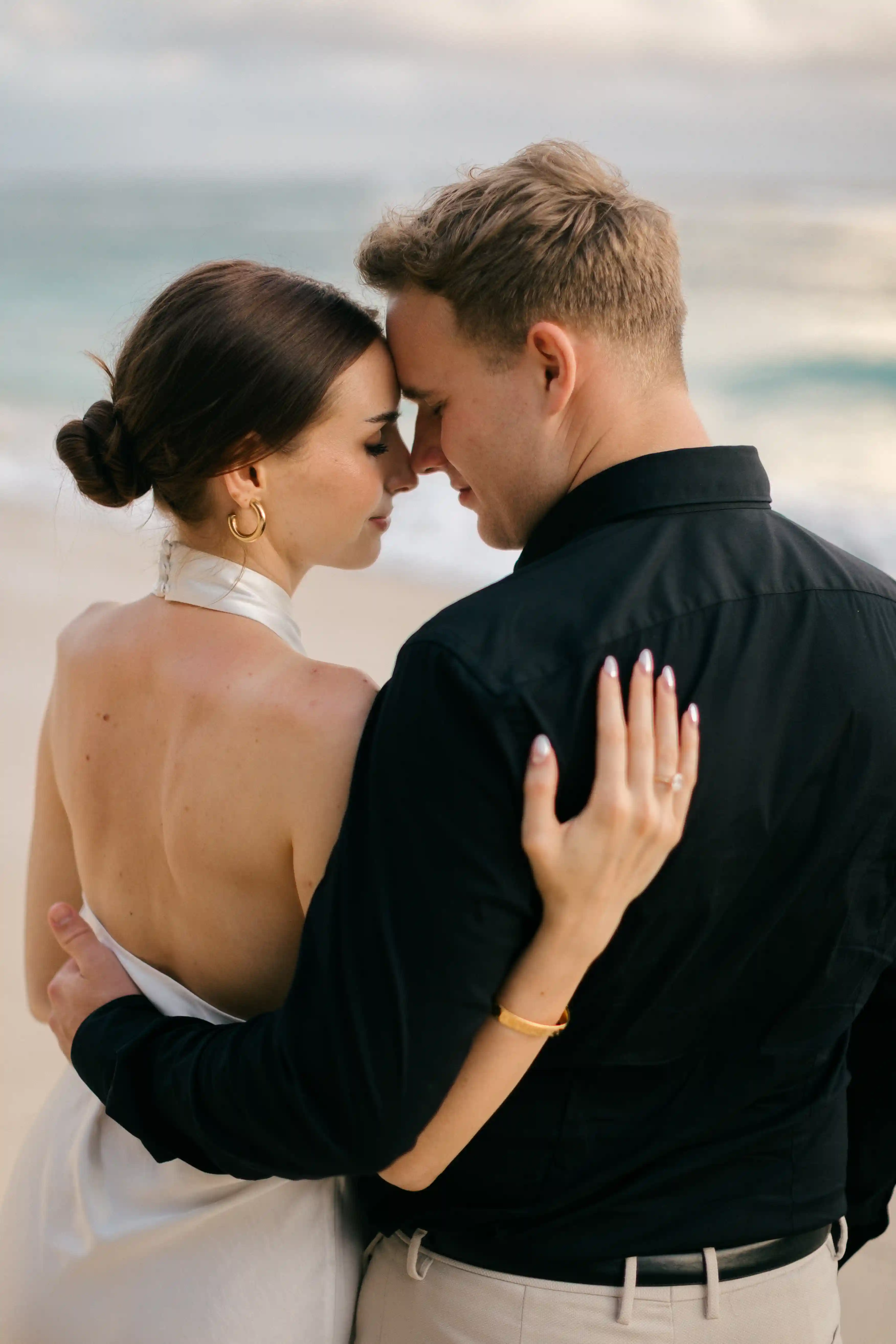 Elegant back-view portrait of the couple embracing by the shoreline.