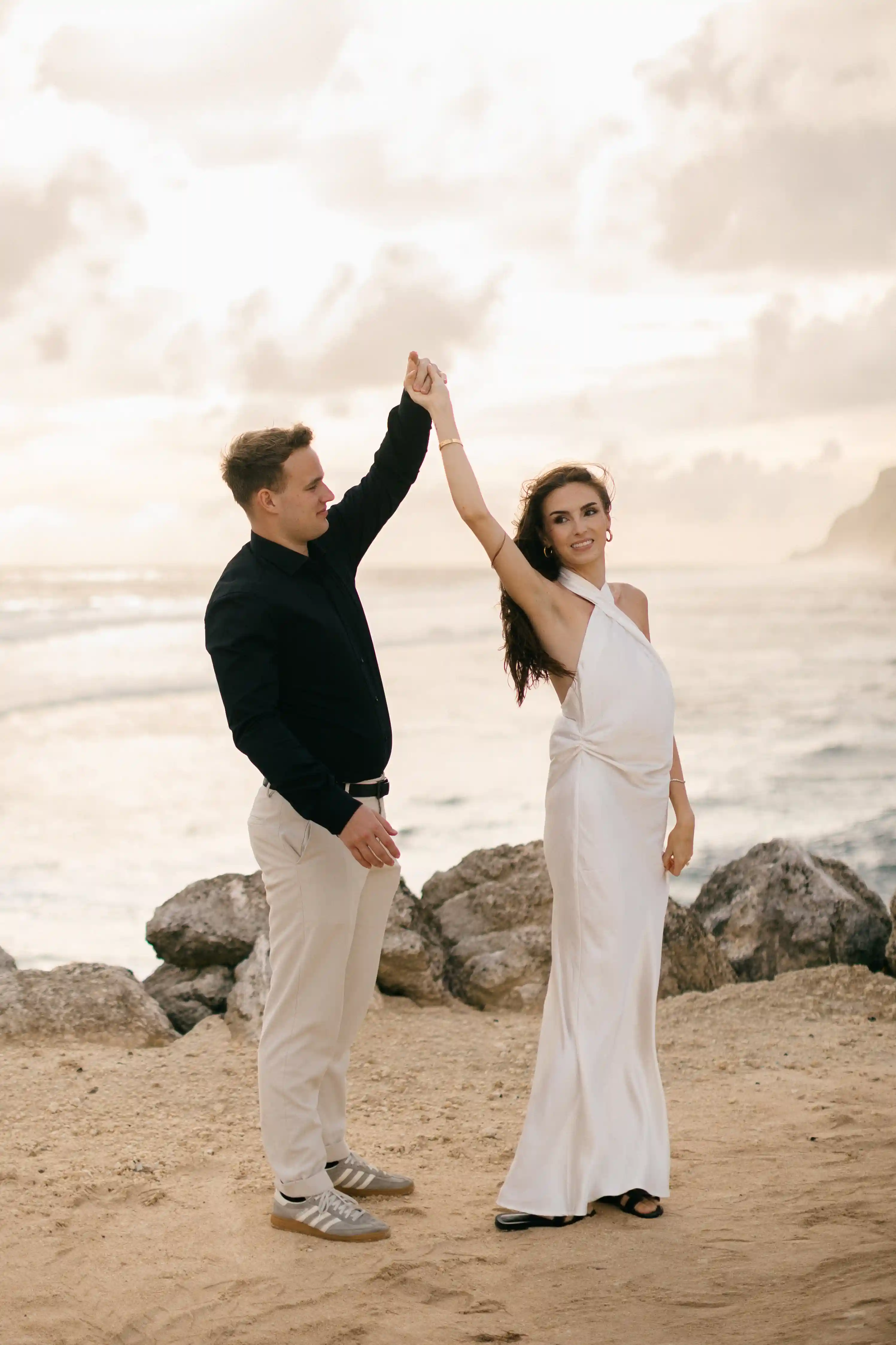 Celebration moment as Lucas lifts Jasmin’s hand in joy on the beach.