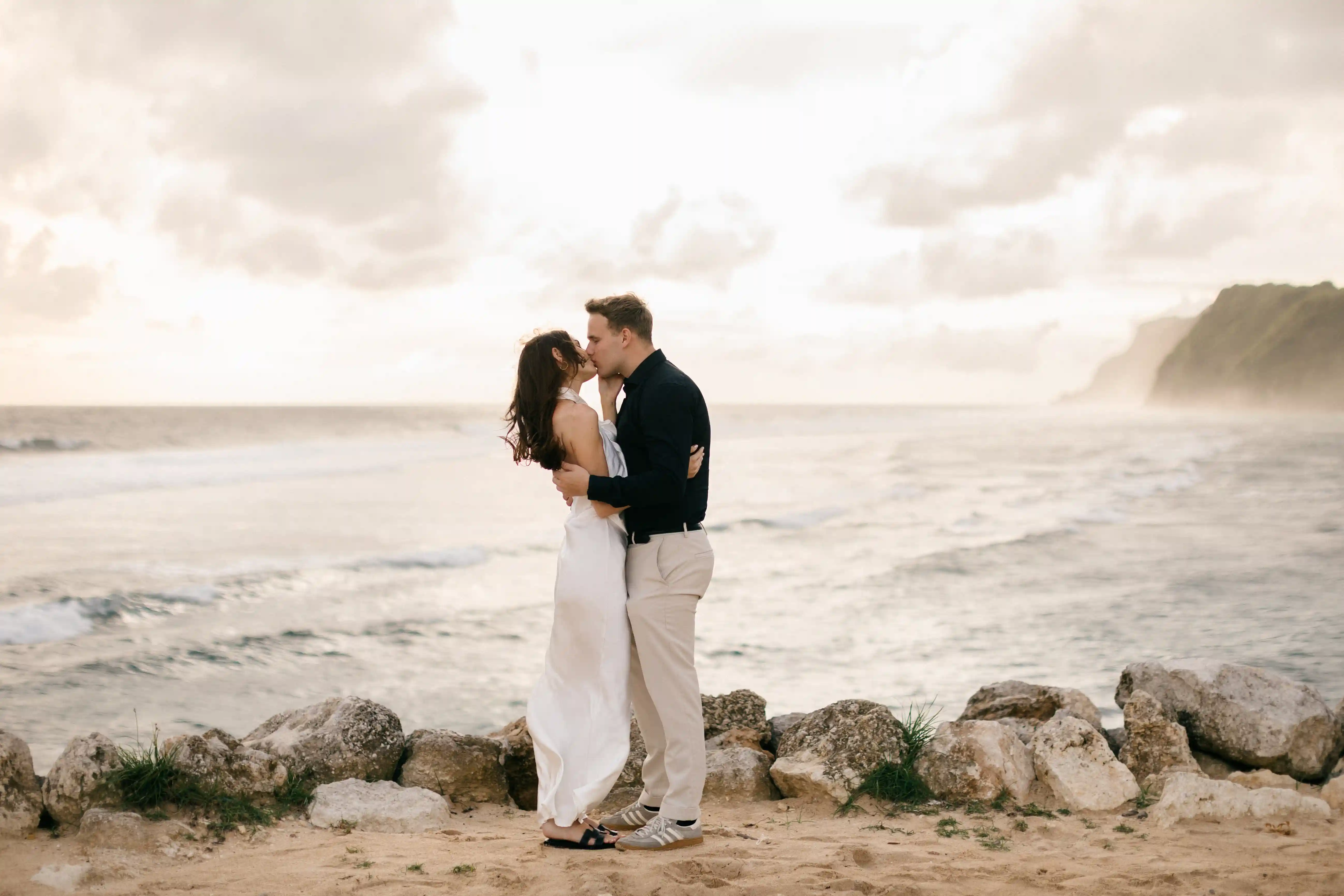 Romantic sunset embrace with ocean waves in the background.