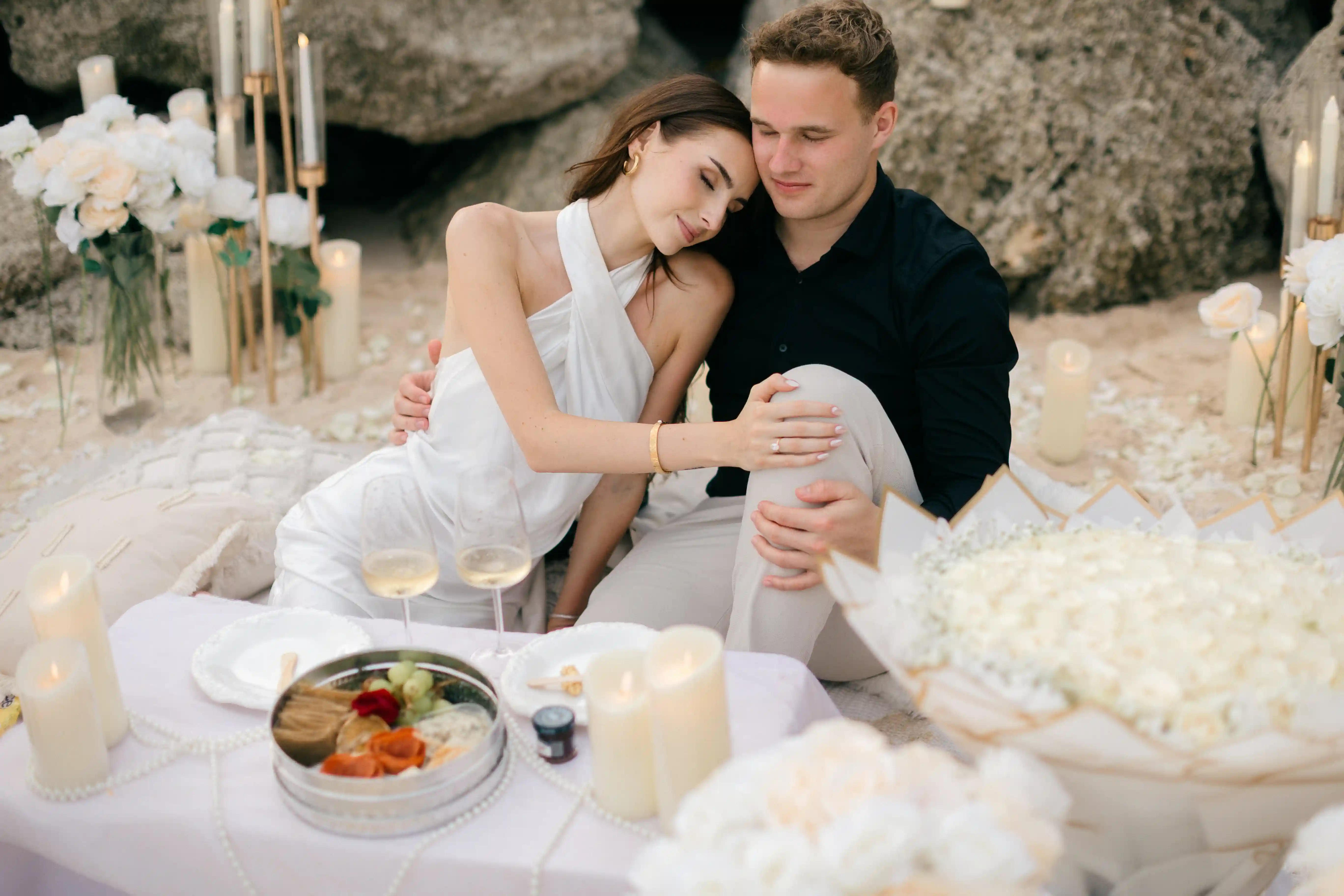 Cozy picnic moment with champagne and floral styling after the proposal.