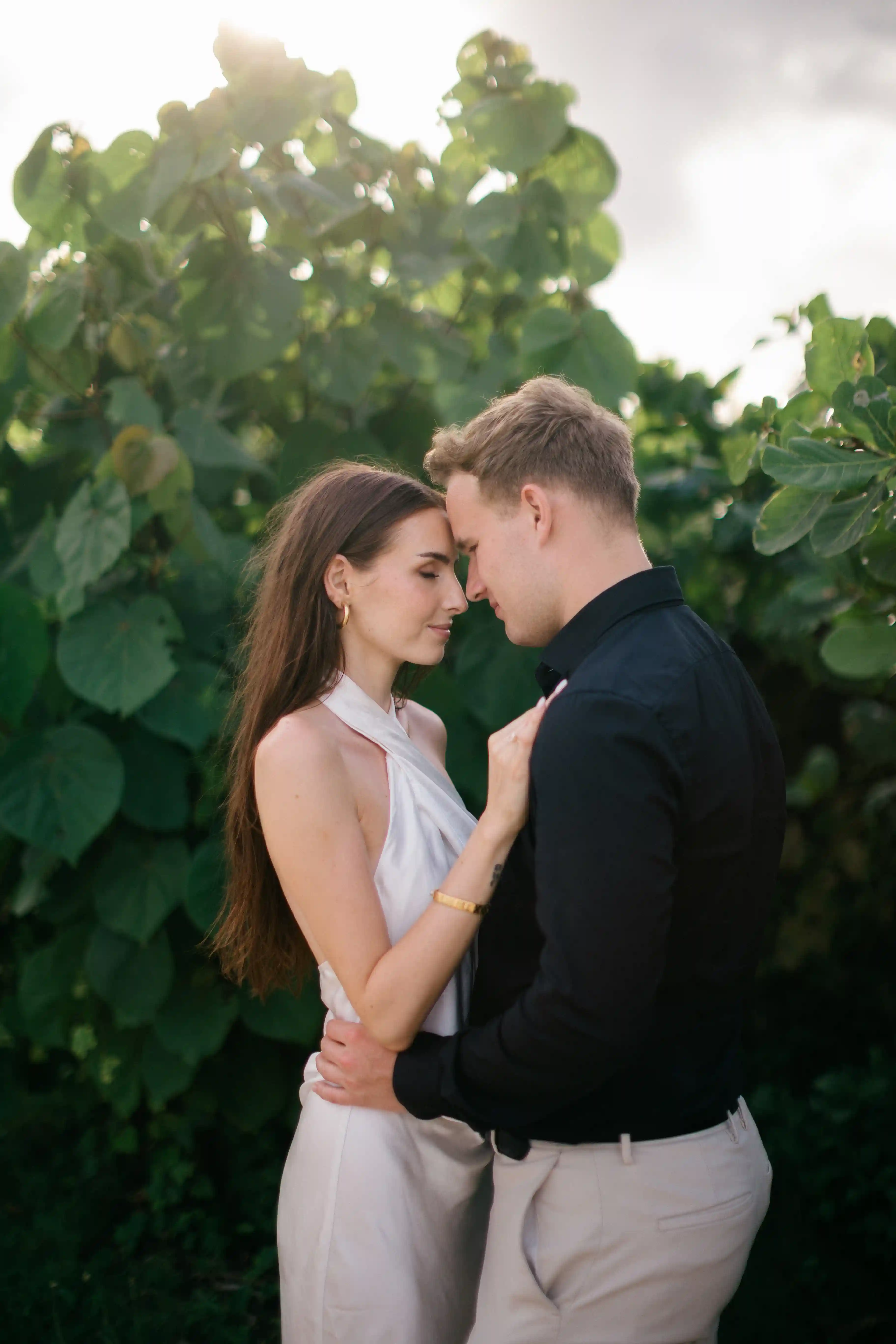 Intimate couple portrait surrounded by lush green tropical plants.