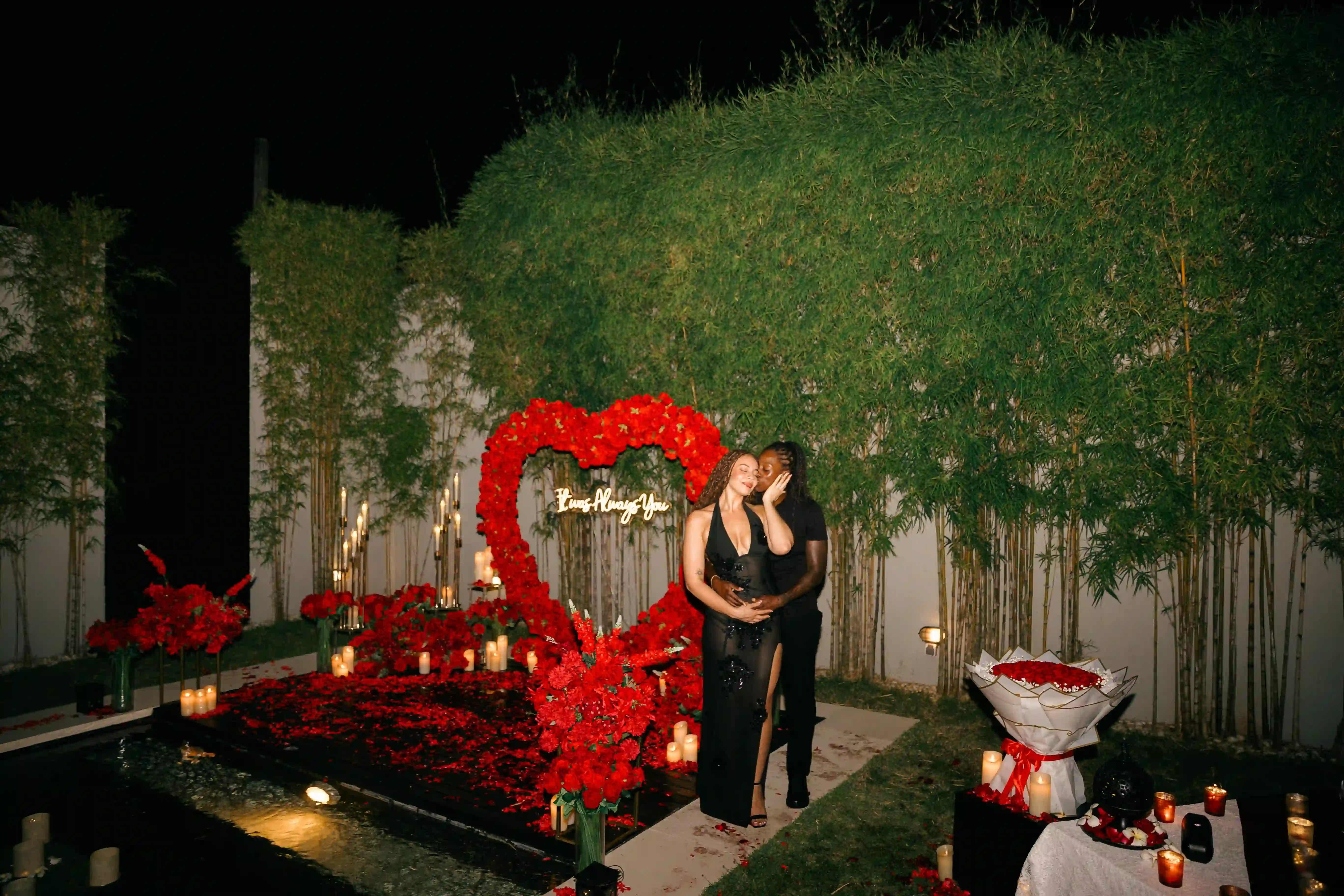 Romantic Bali villa proposal setup with candlelight and red rose heart arch
