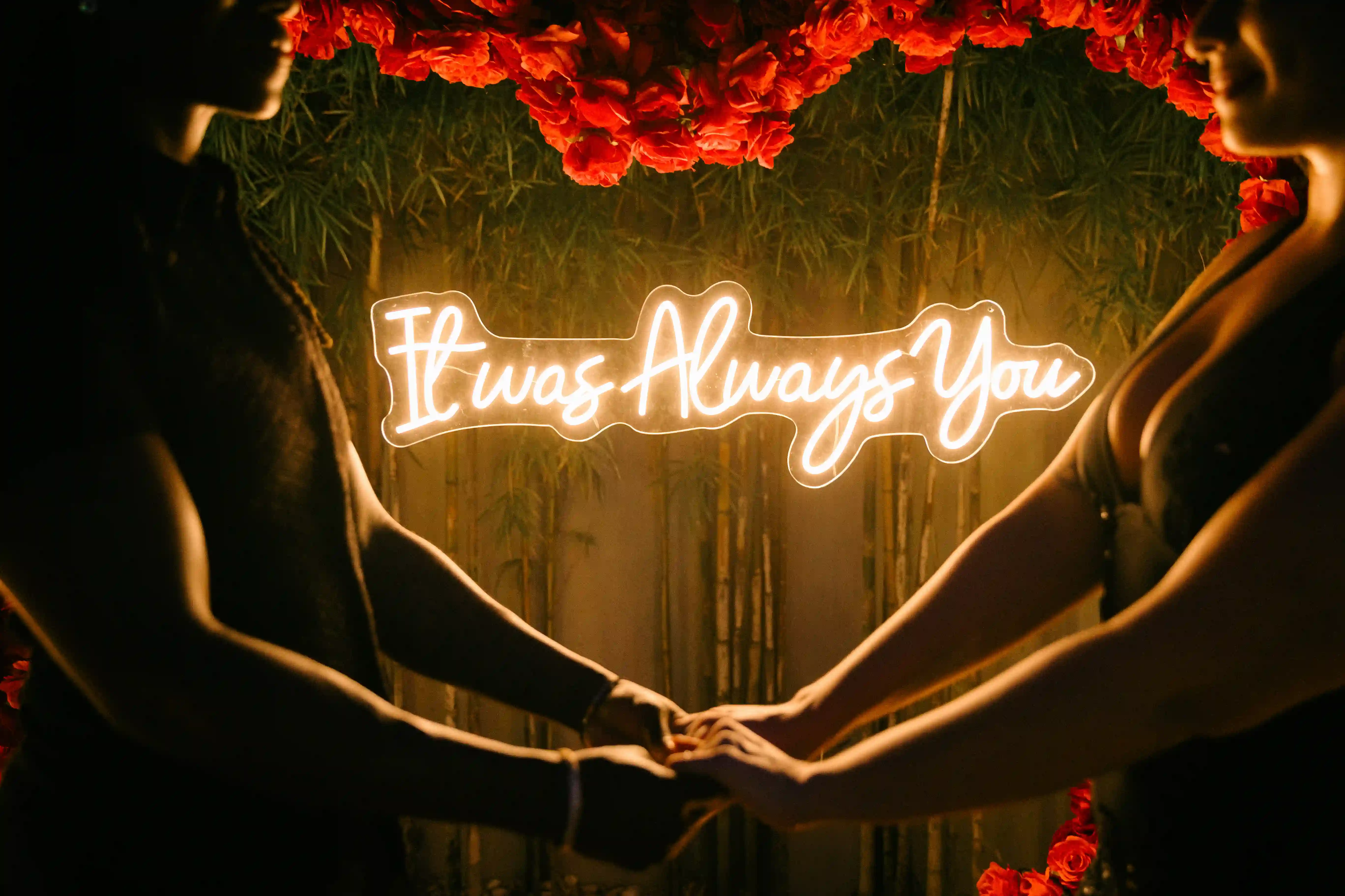 Glowing “It Was Always You” neon sign surrounded by red roses at Bali proposal setup