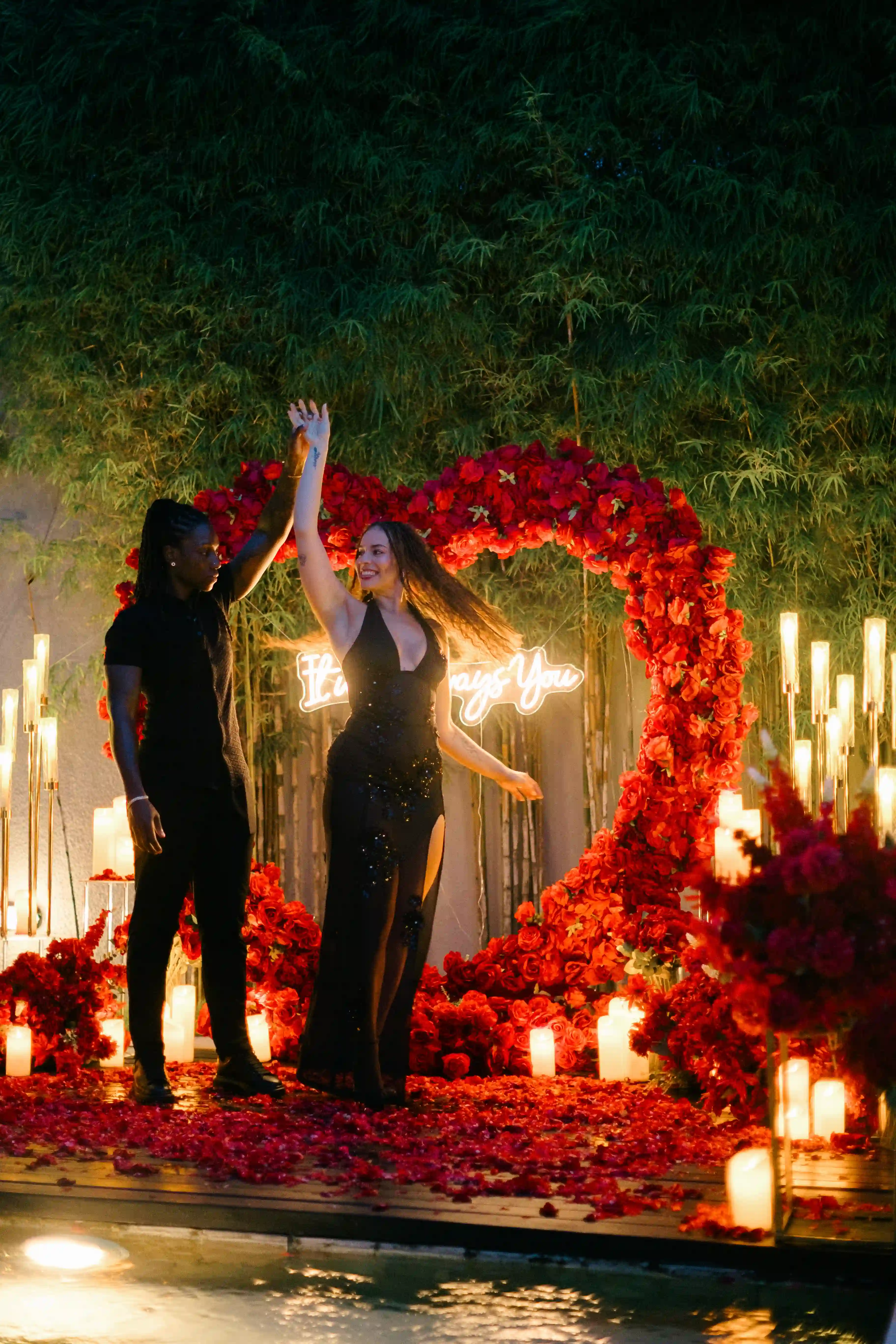 Engagement moment in front of heart-shaped rose arrangement during Bali proposal