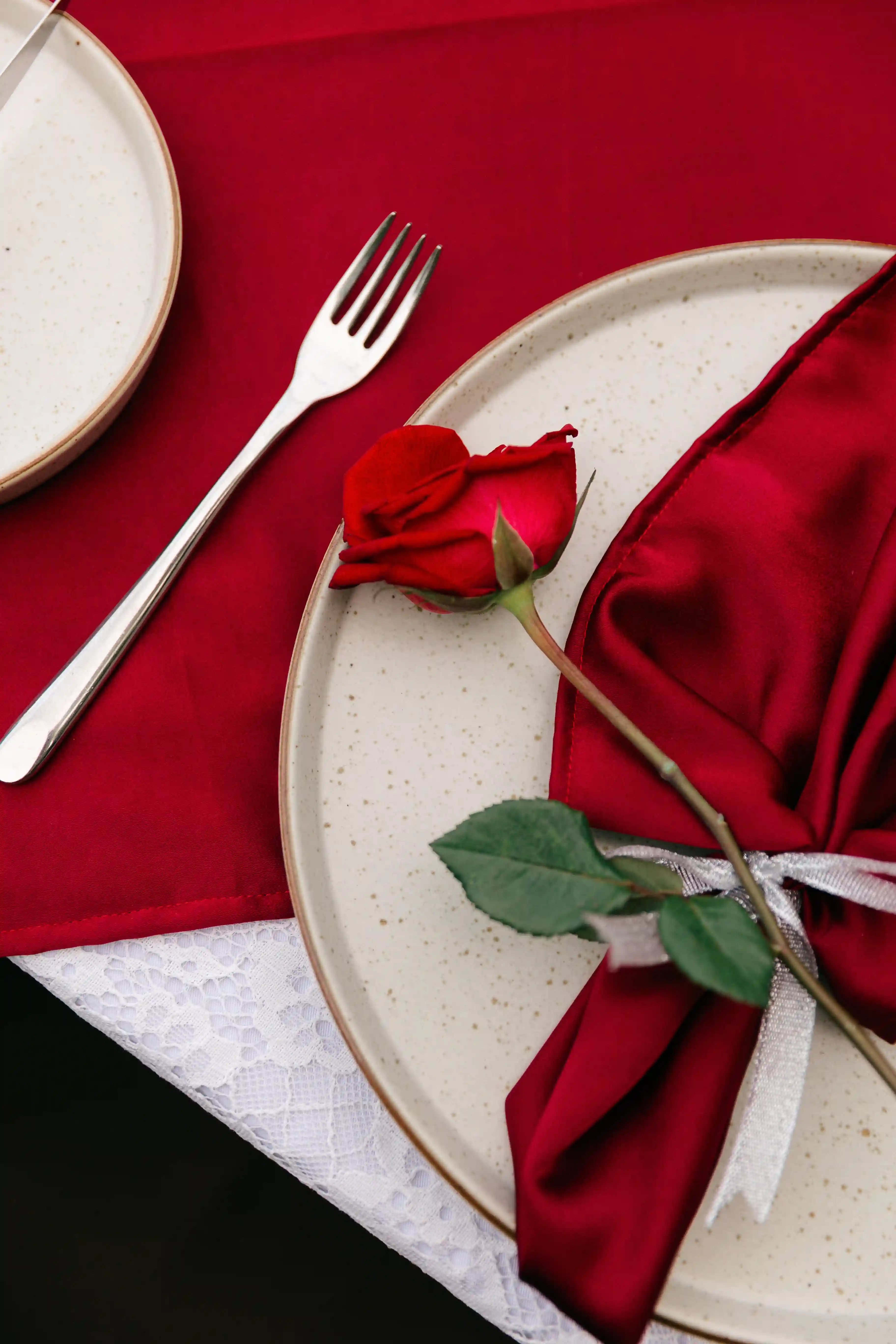 Romantic dinner detail with red rose and elegant table setting at Bali villa