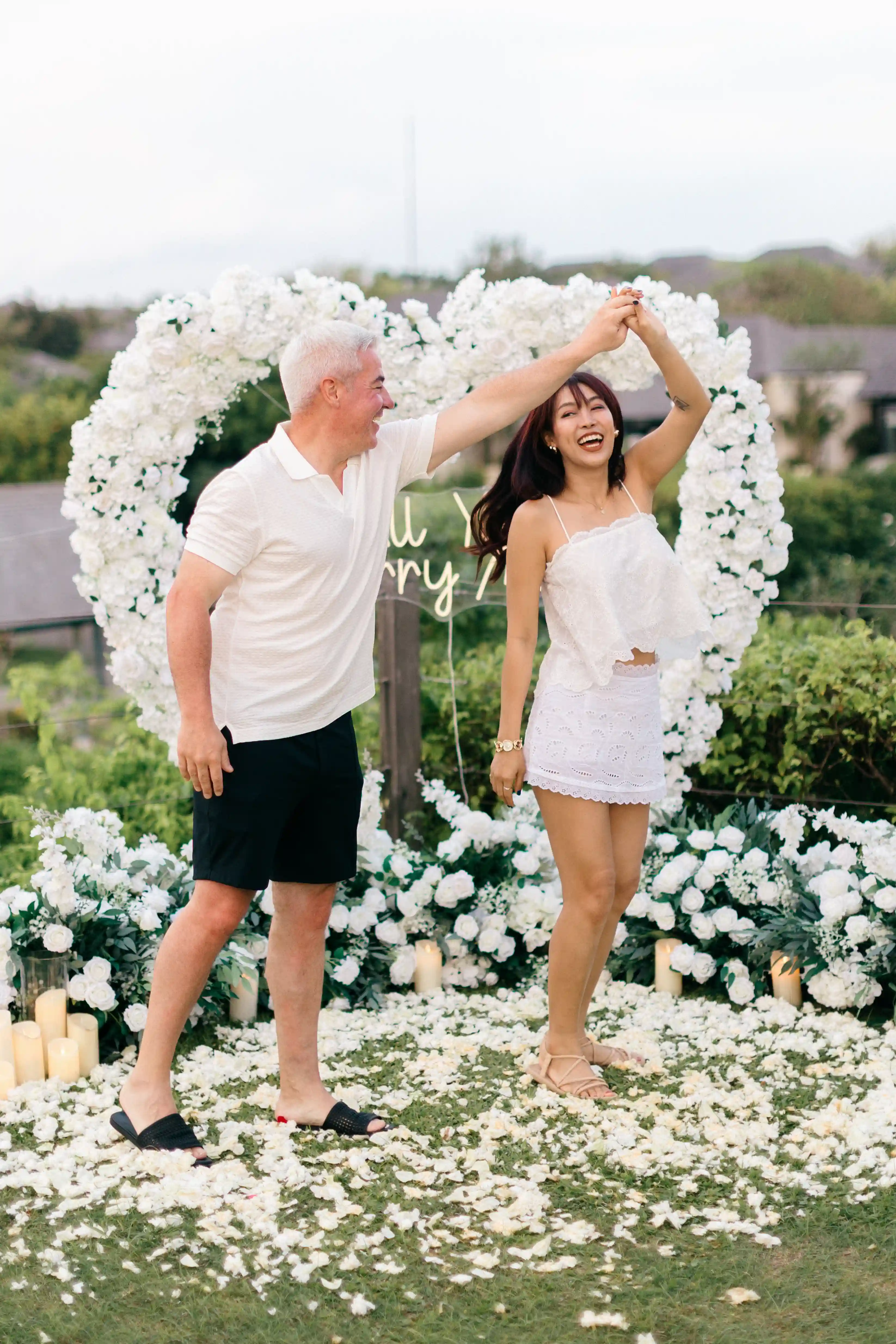 Couple posing together under heart-shaped floral arch in Bali