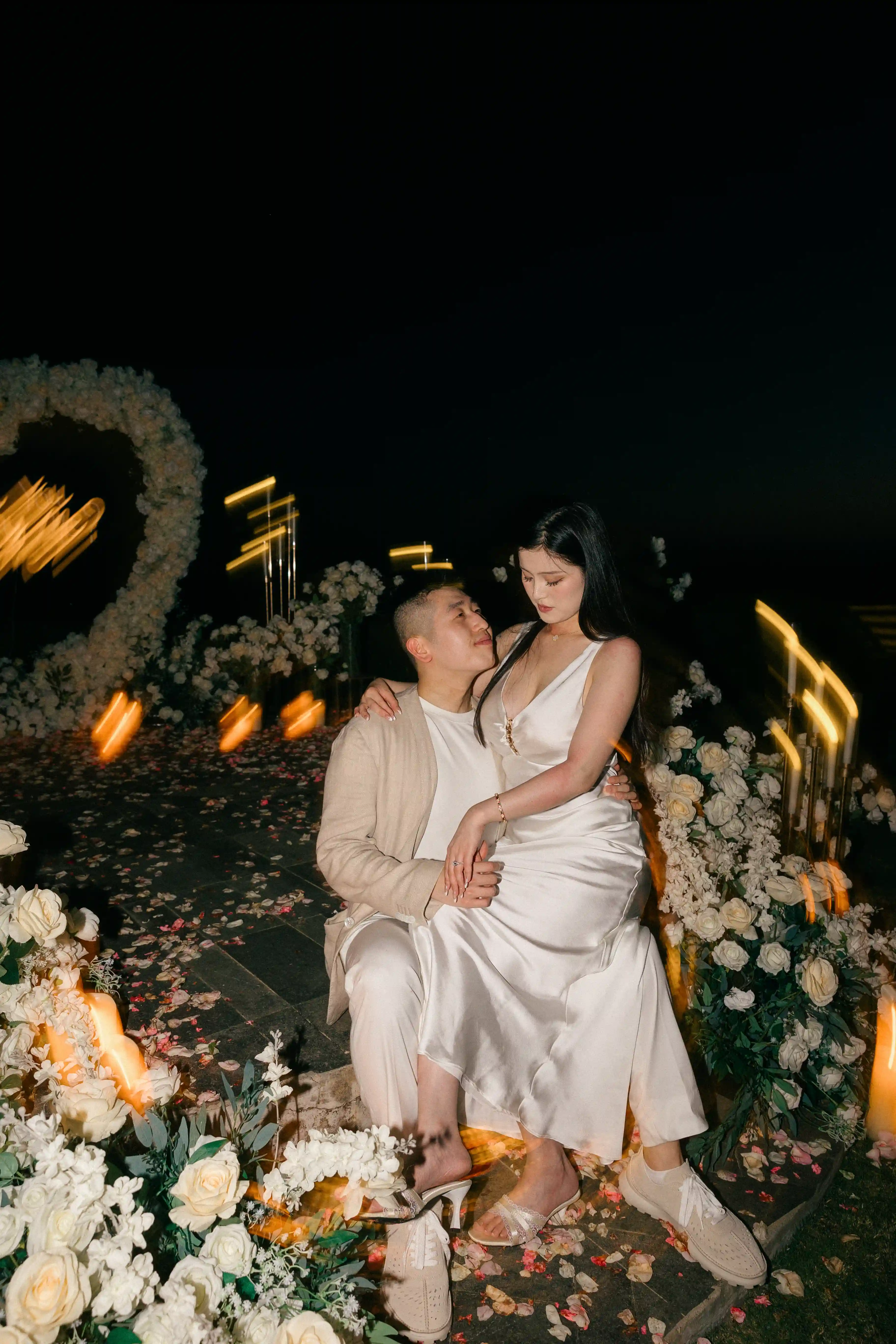 Couple embracing at a candlelit cliffside proposal setup in Bali