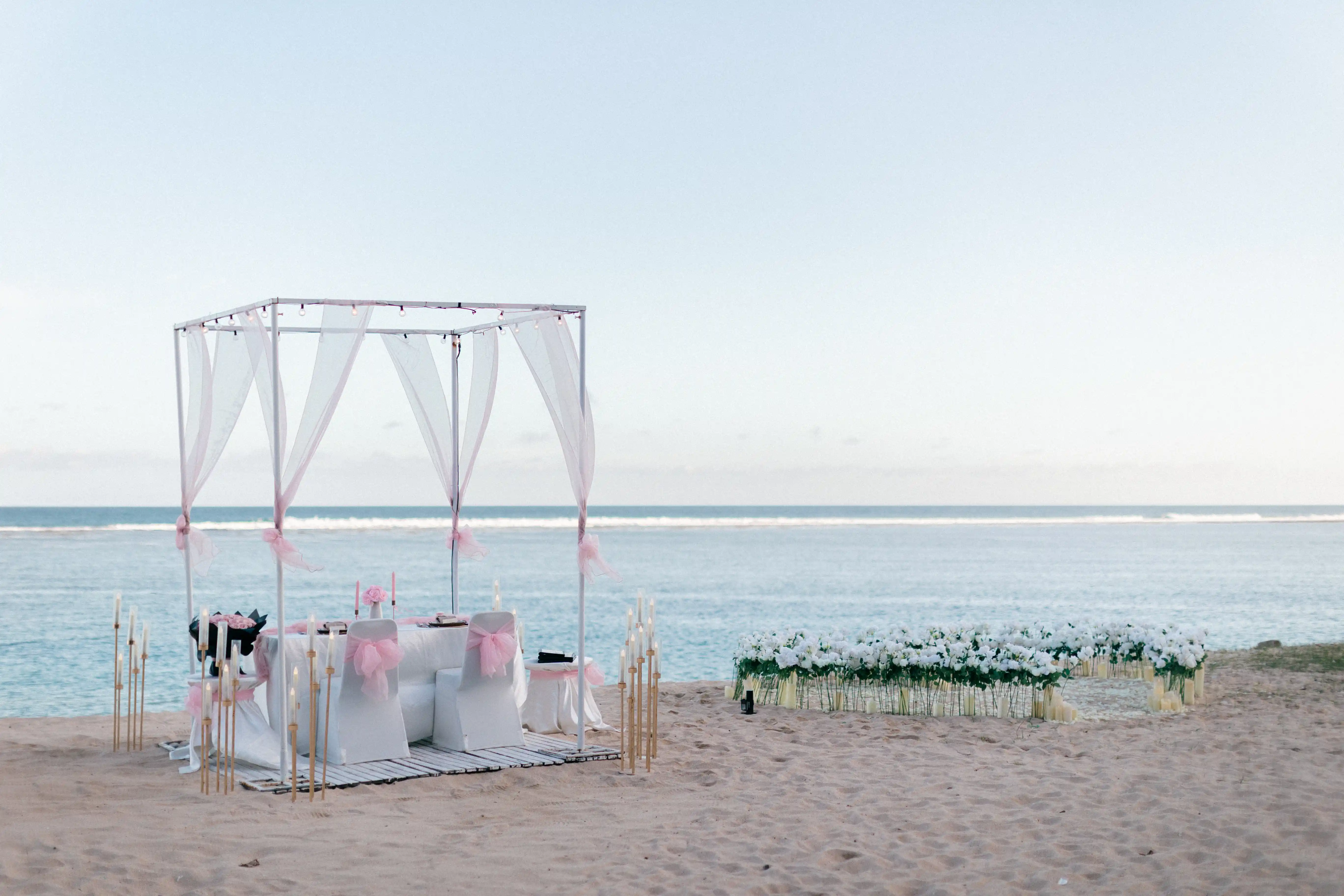 Luxury beachfront dinner setup on white sand beach in Bali