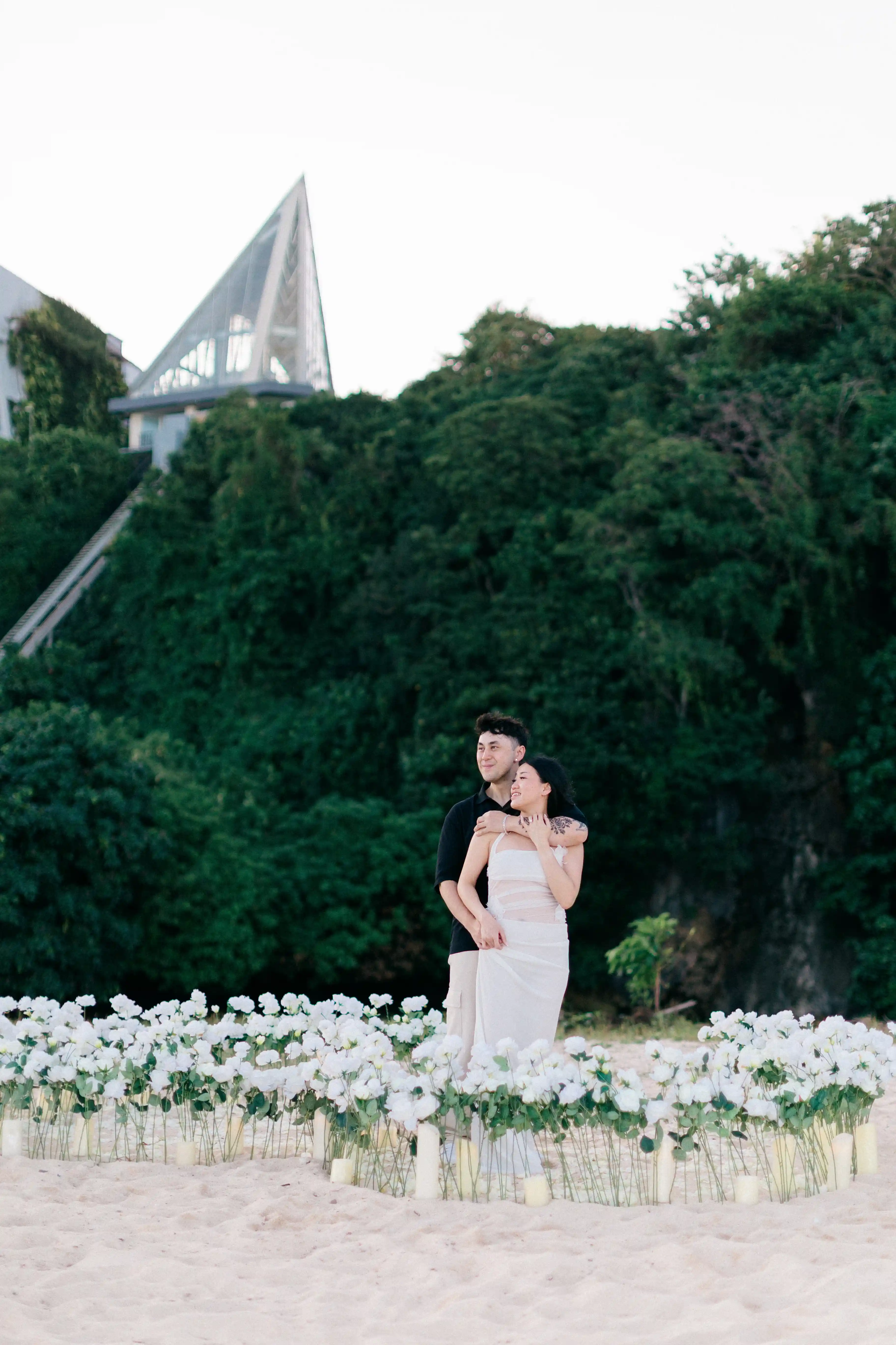 Bride posing after beach proposal in Bali with tropical cliff backdrop