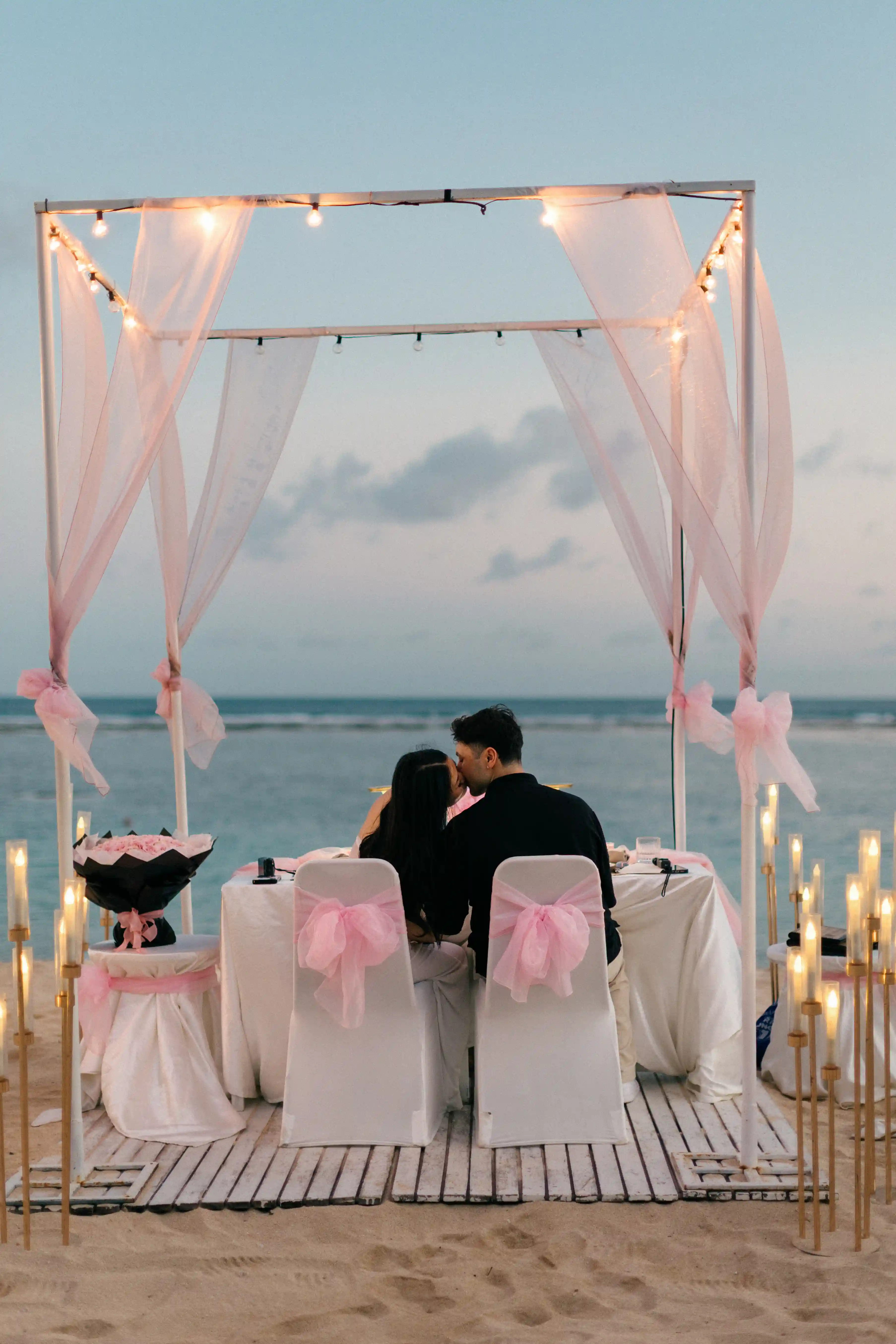 Romantic beachfront dinner setup during sunset proposal in Bali