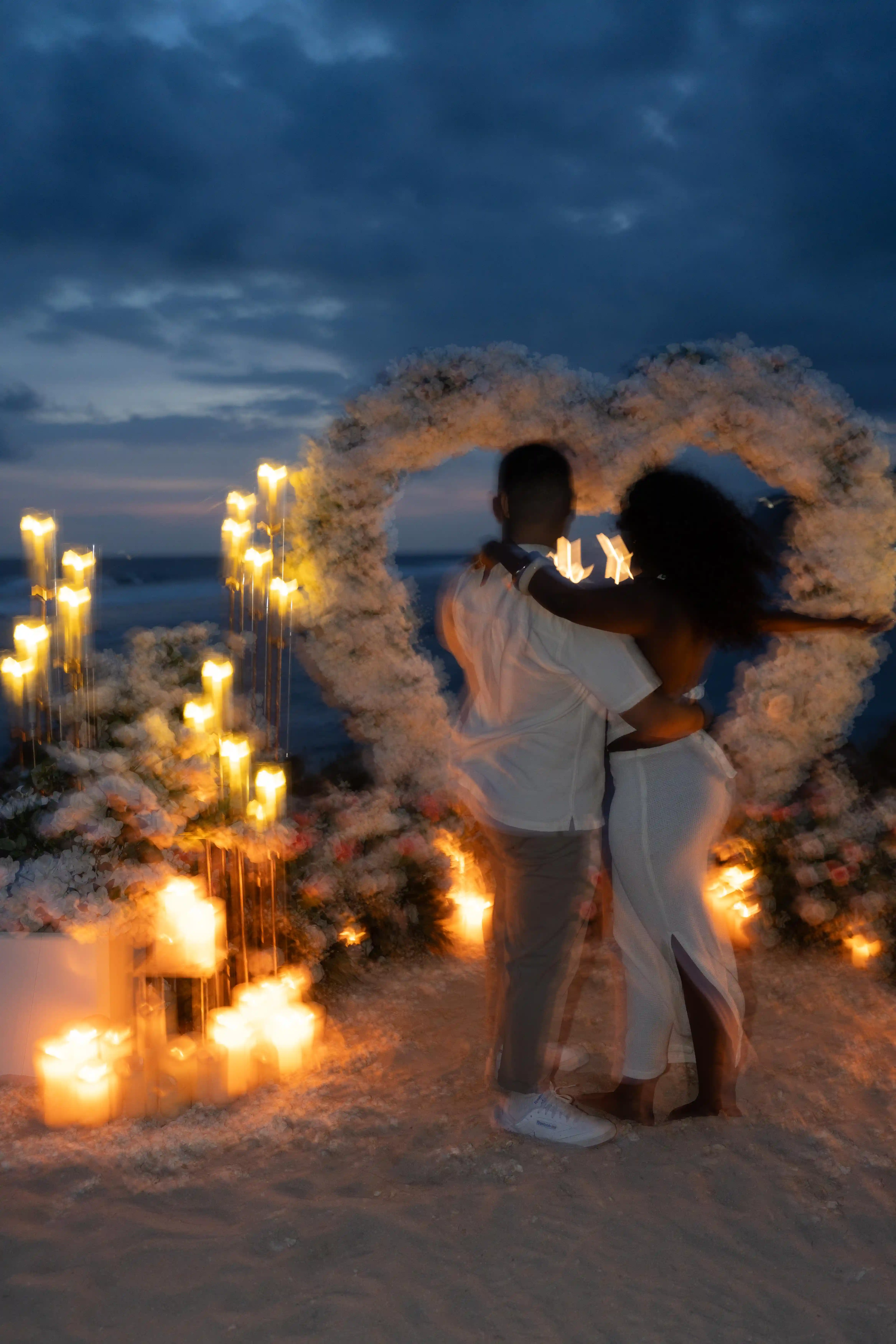 Couple embracing during candlelit beach proposal at night in Bali