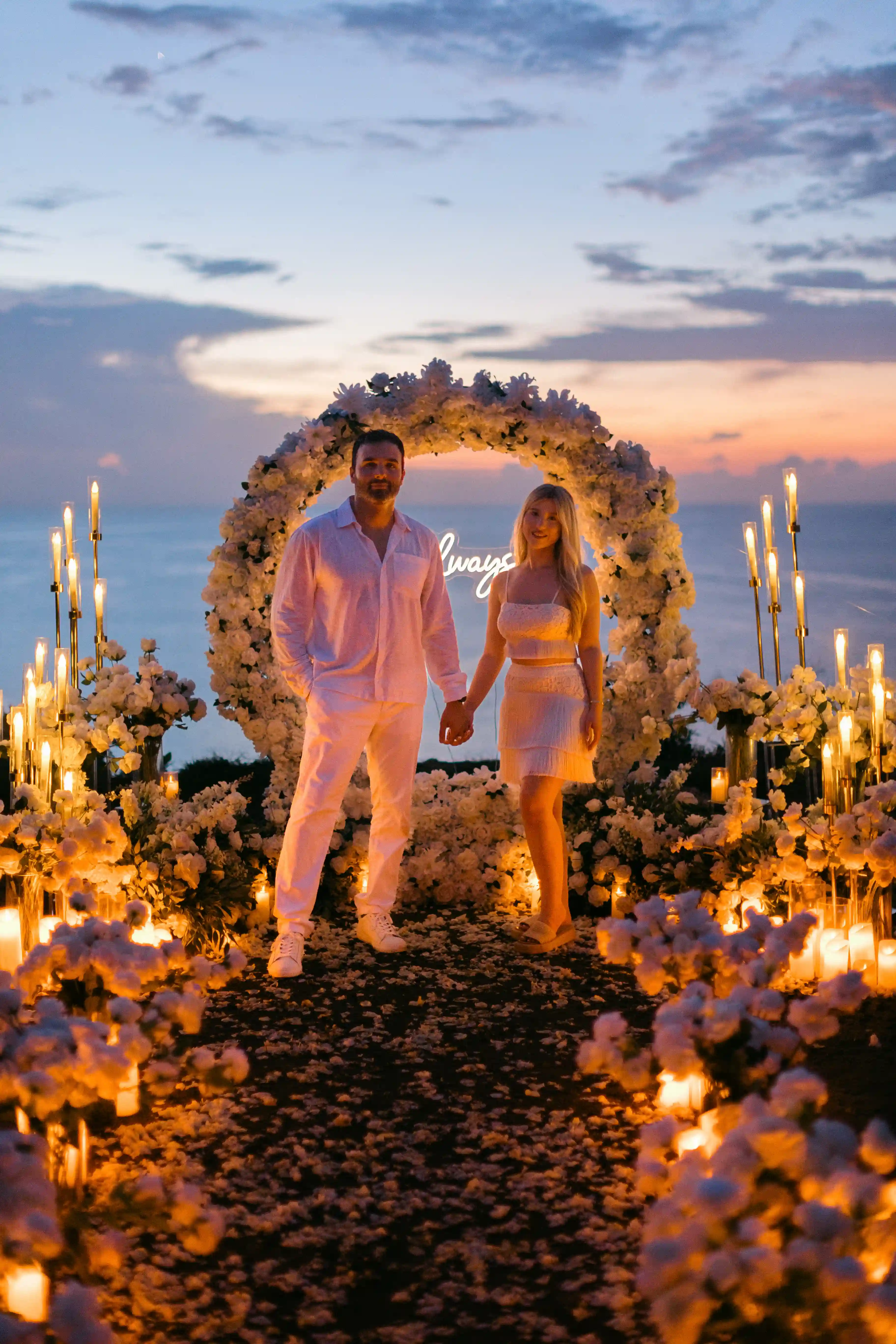 Candlelit floral proposal arch overlooking the ocean at sunset in Bali