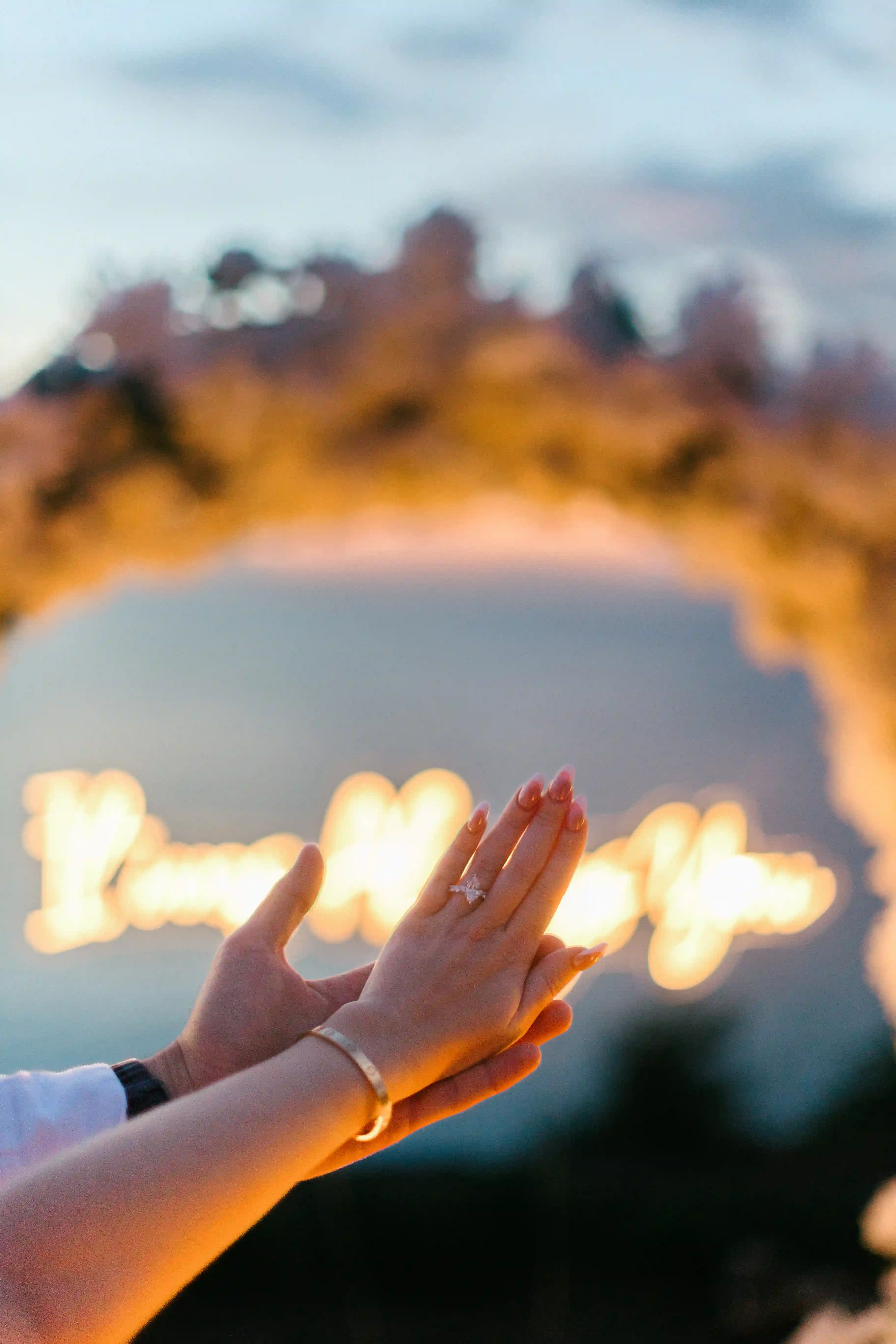 Hand reaching toward glowing candlelight at romantic Bali proposal setup