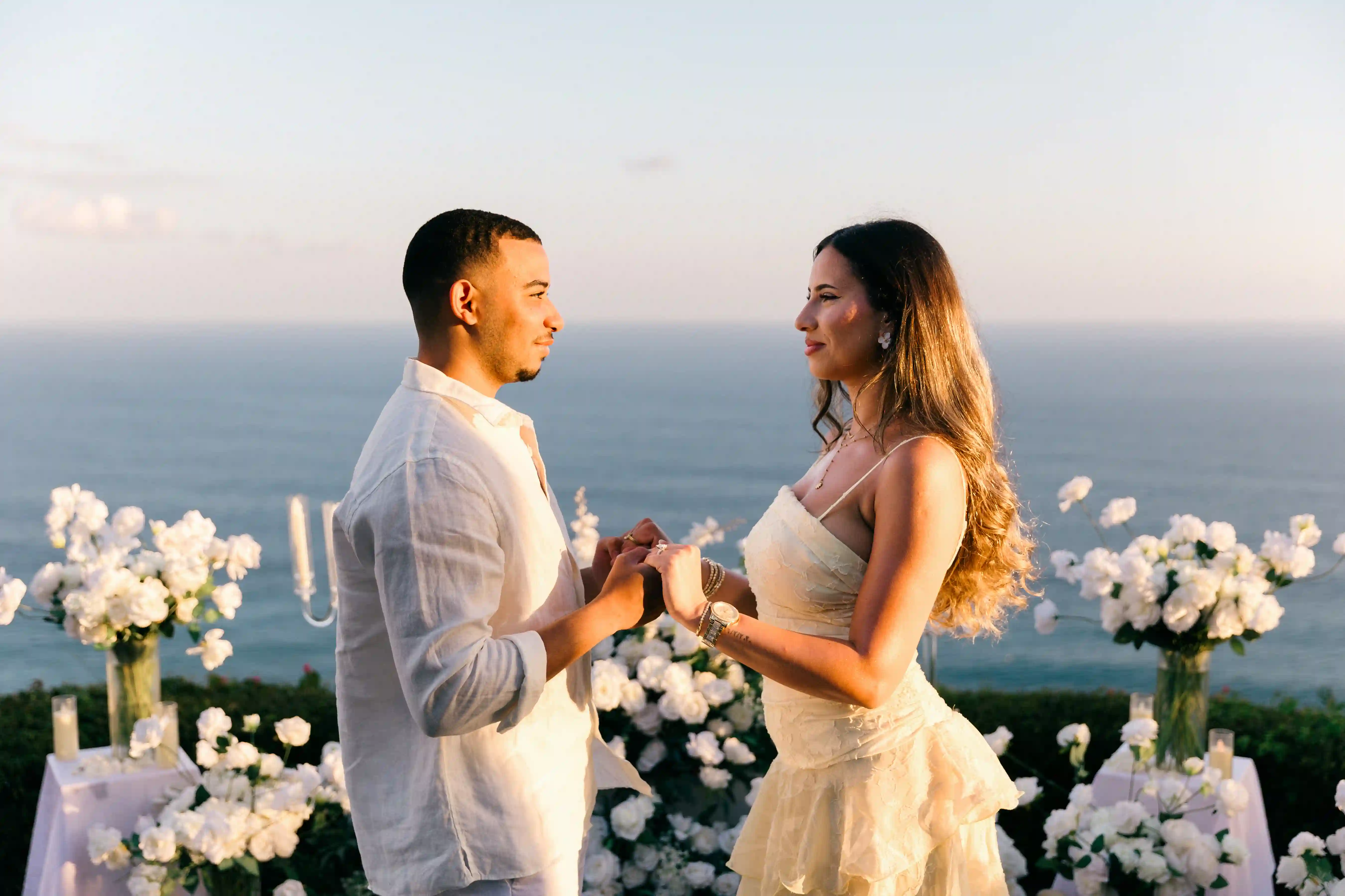 Couple exchanging a bouquet at a clifftop proposal above the ocean in Bali