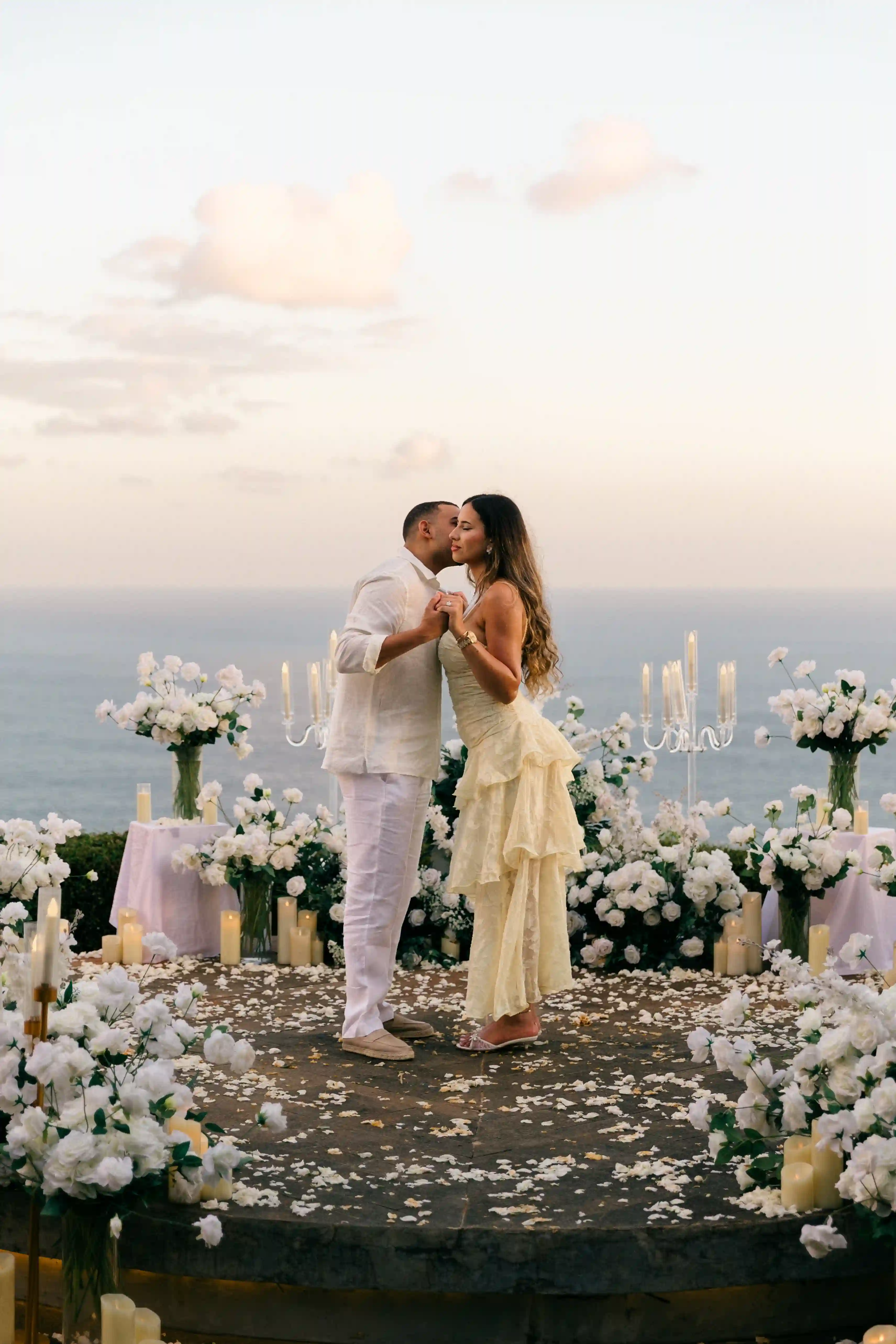 Couple kissing at a white floral cliff proposal in Bali