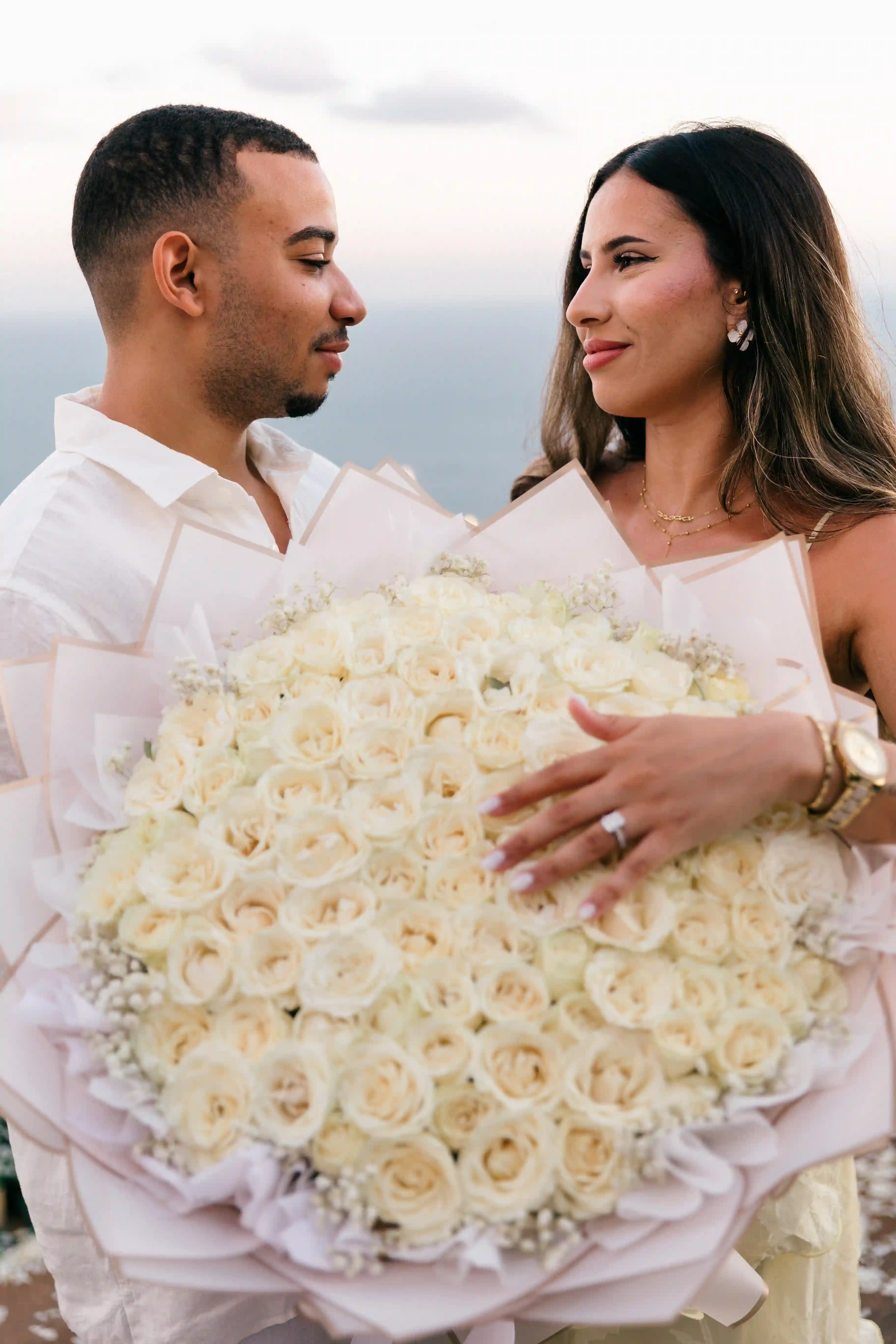 Man holding a large white rose bouquet at a Bali cliff proposal