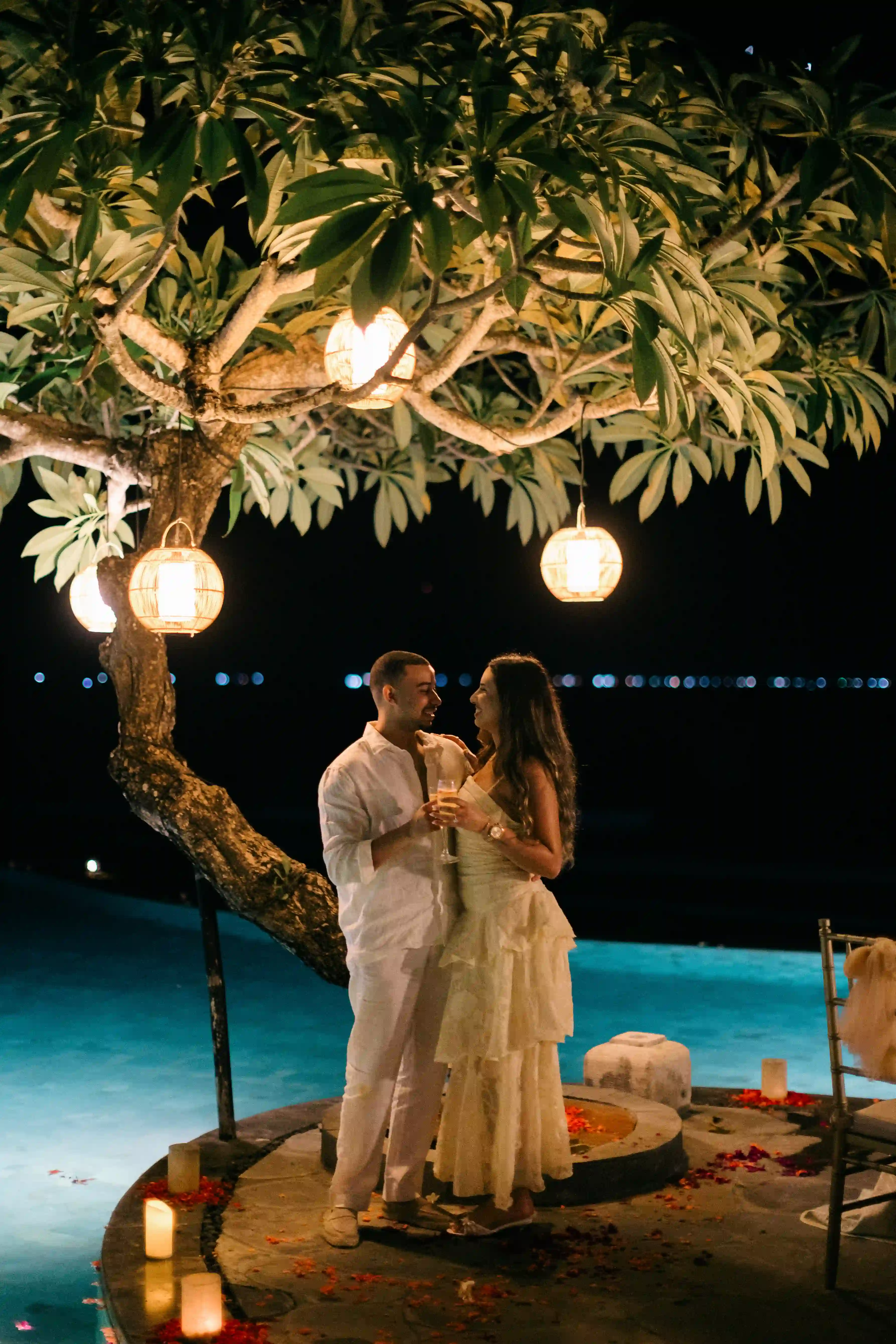 Couple at a candlelit dinner under a frangipani tree in Bali at night