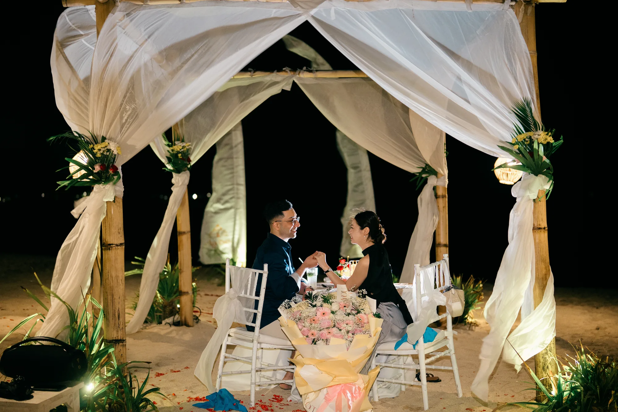 Romantic beach dinner setup in a draped cabana for a Bali proposal