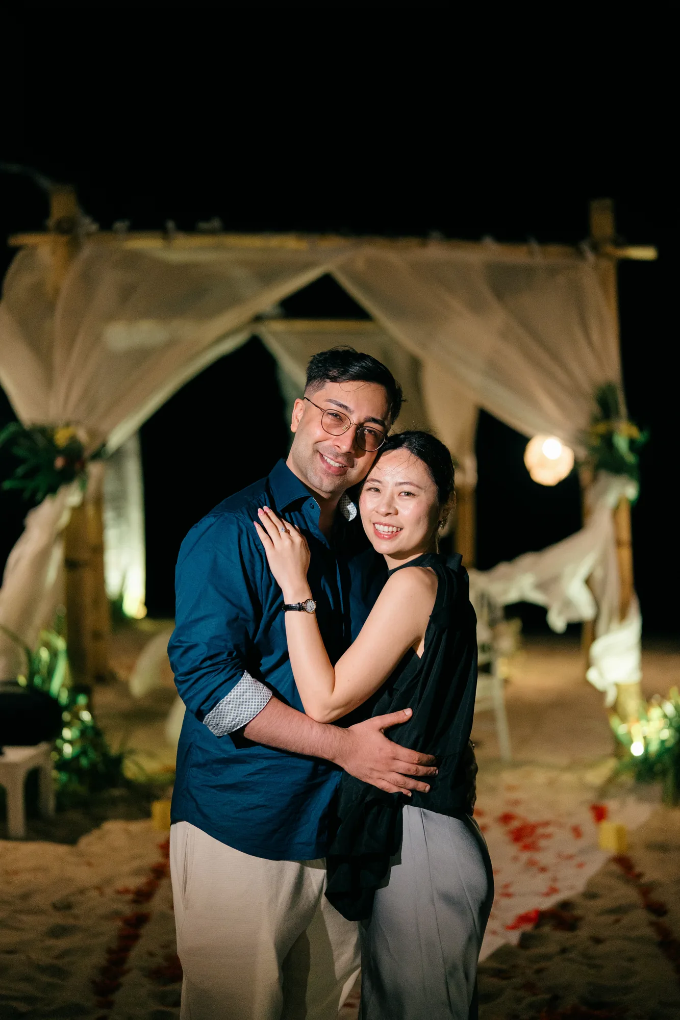 Couple embracing at their beach cabana at night after a Bali proposal