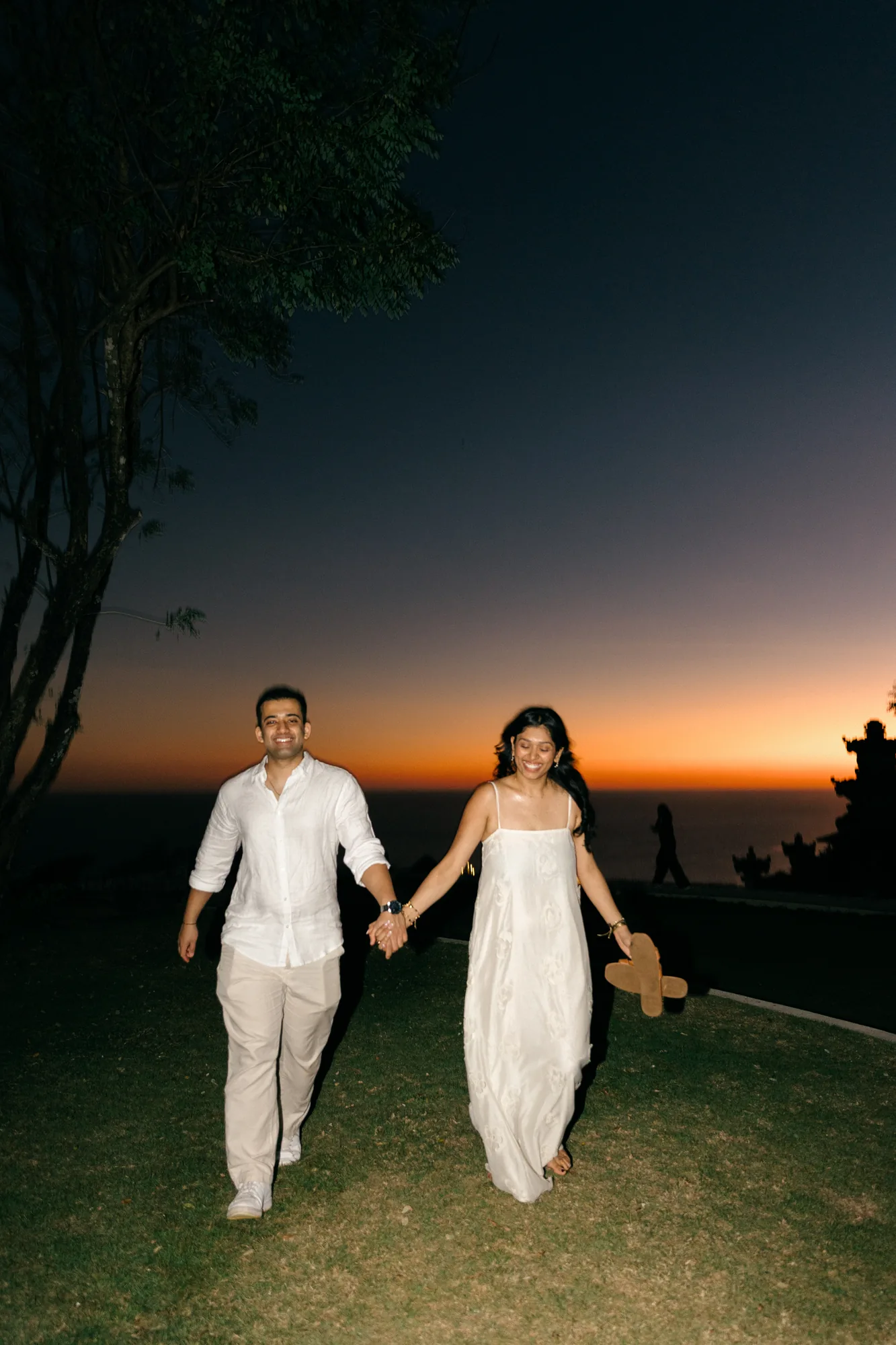 Couple walking hand in hand along the clifftop at sunset during their Bali proposal
