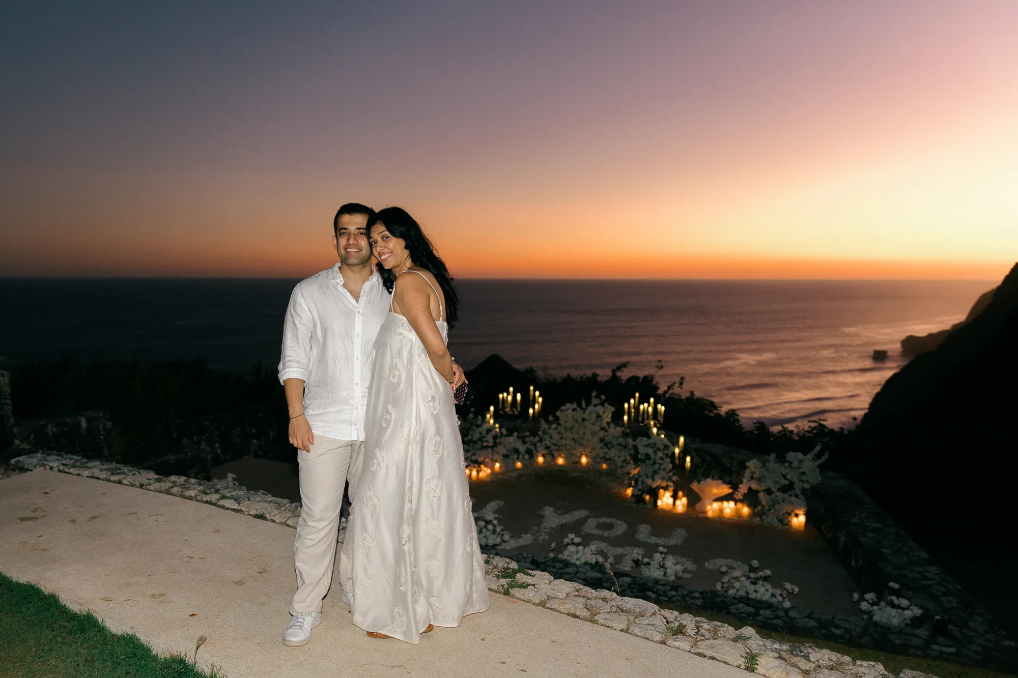 Couple embracing on the cliff above the ocean at sunset during a Bali proposal