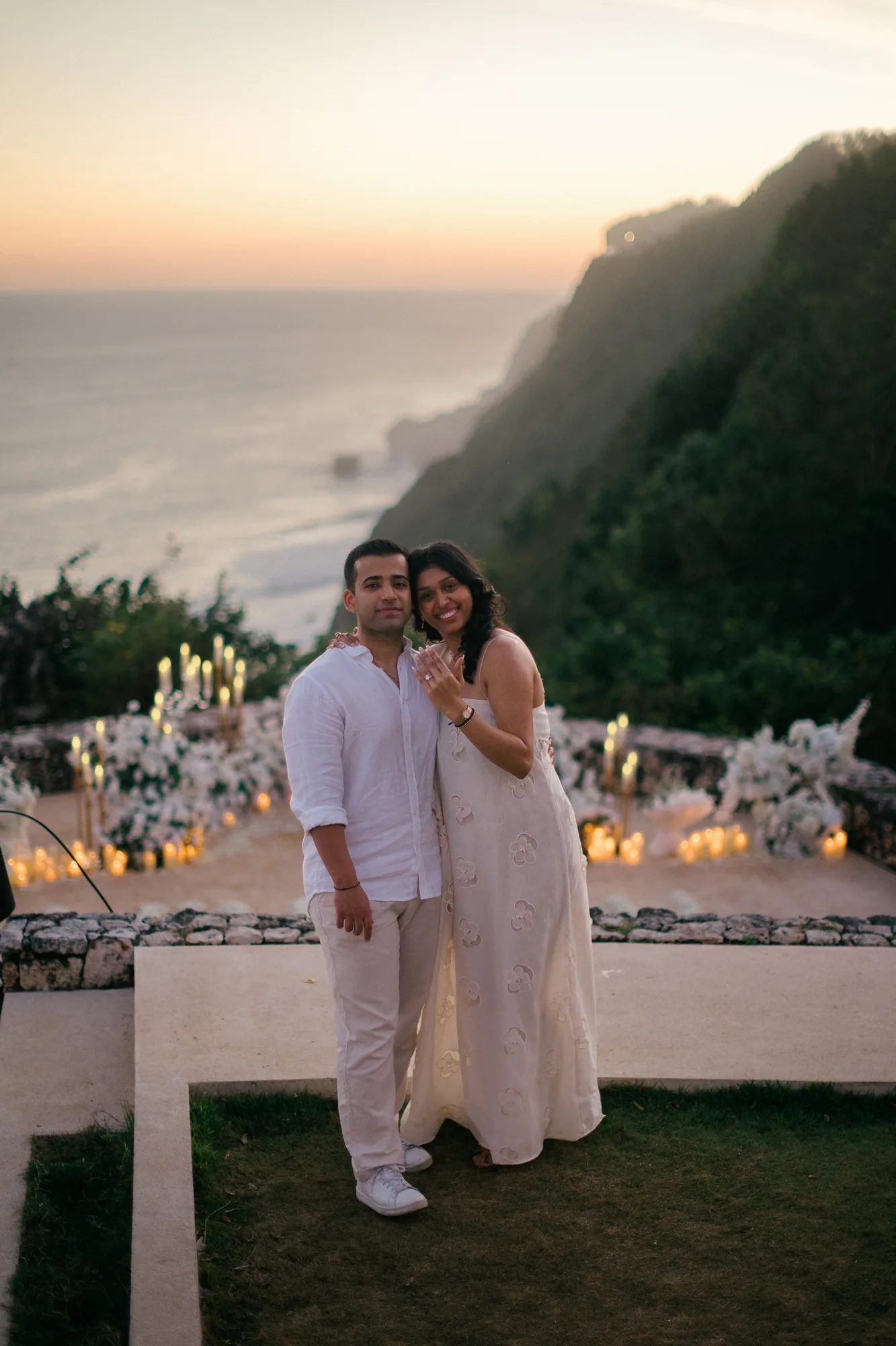 Couple embracing at their clifftop floral setup at sunset during a Bali proposal