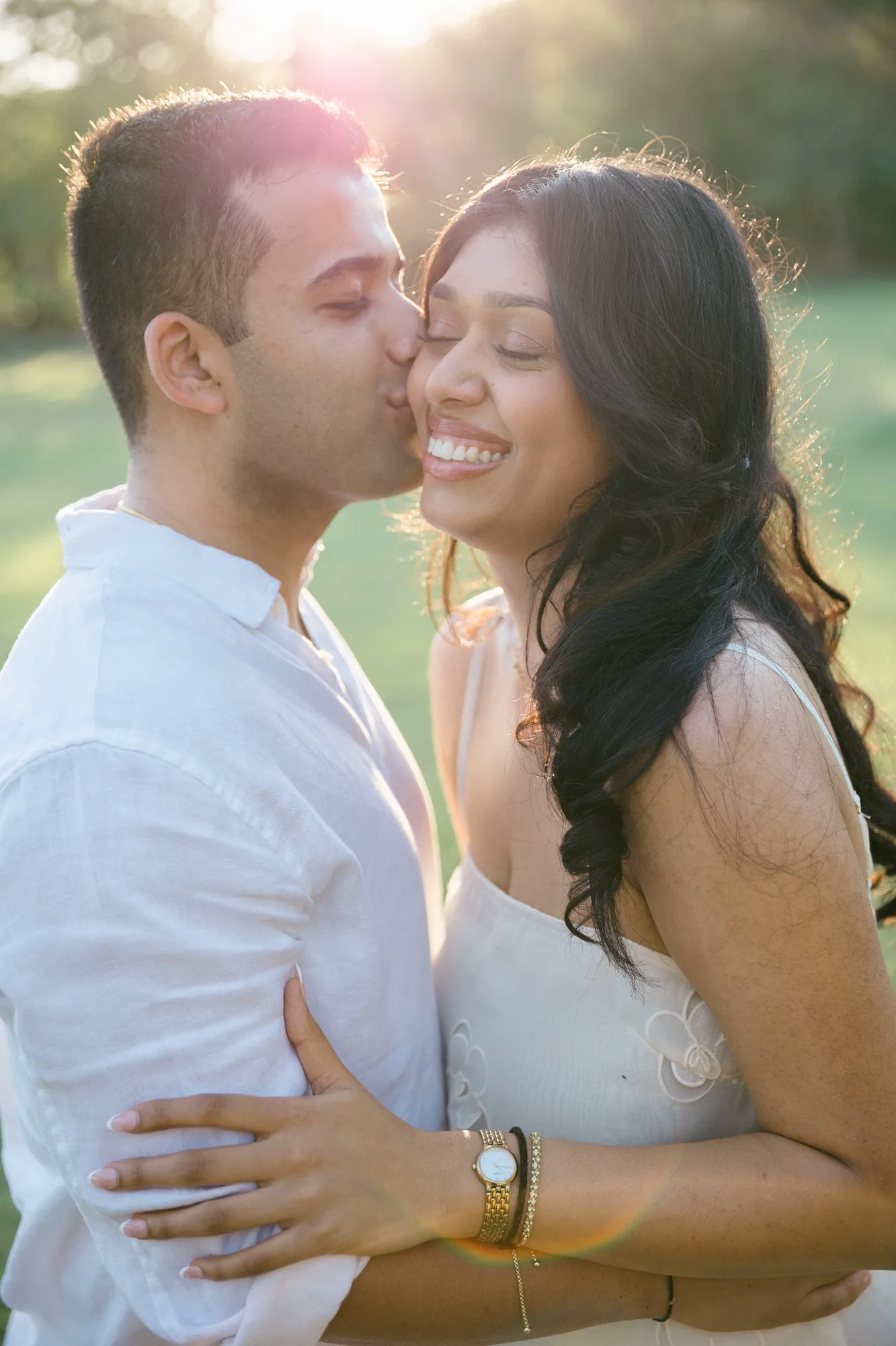 Man kissing his partner's cheek in golden-hour light in a garden after a Bali proposal