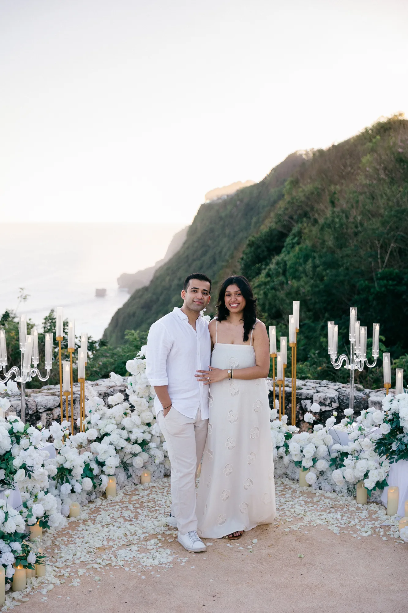 Couple at their candlelit clifftop floral proposal setup during a Bali proposal