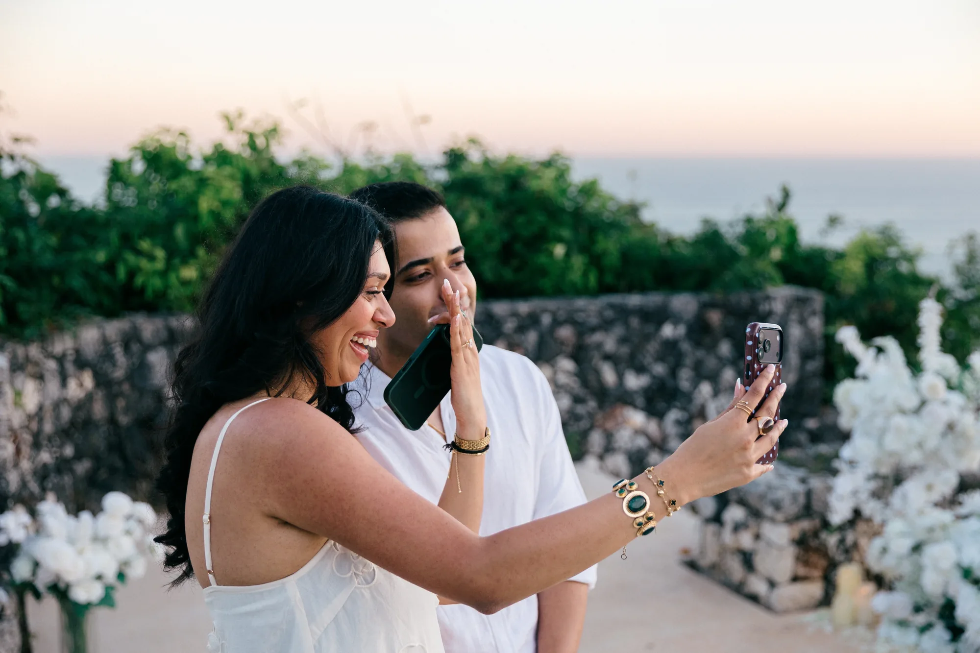 Couple laughing while taking a selfie at their clifftop Bali proposal