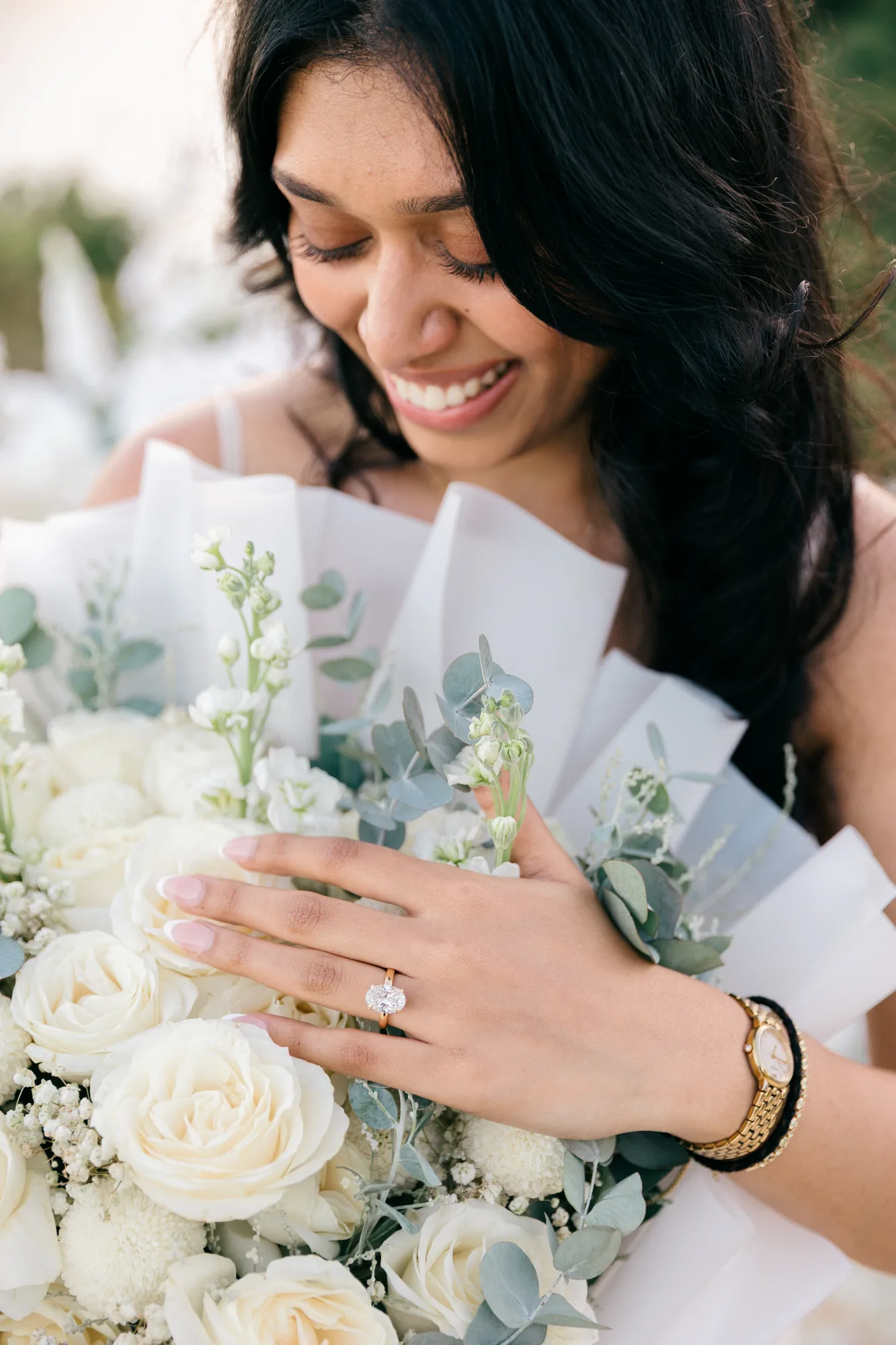 Smiling newly engaged woman holding a white bouquet and showing her ring in Bali