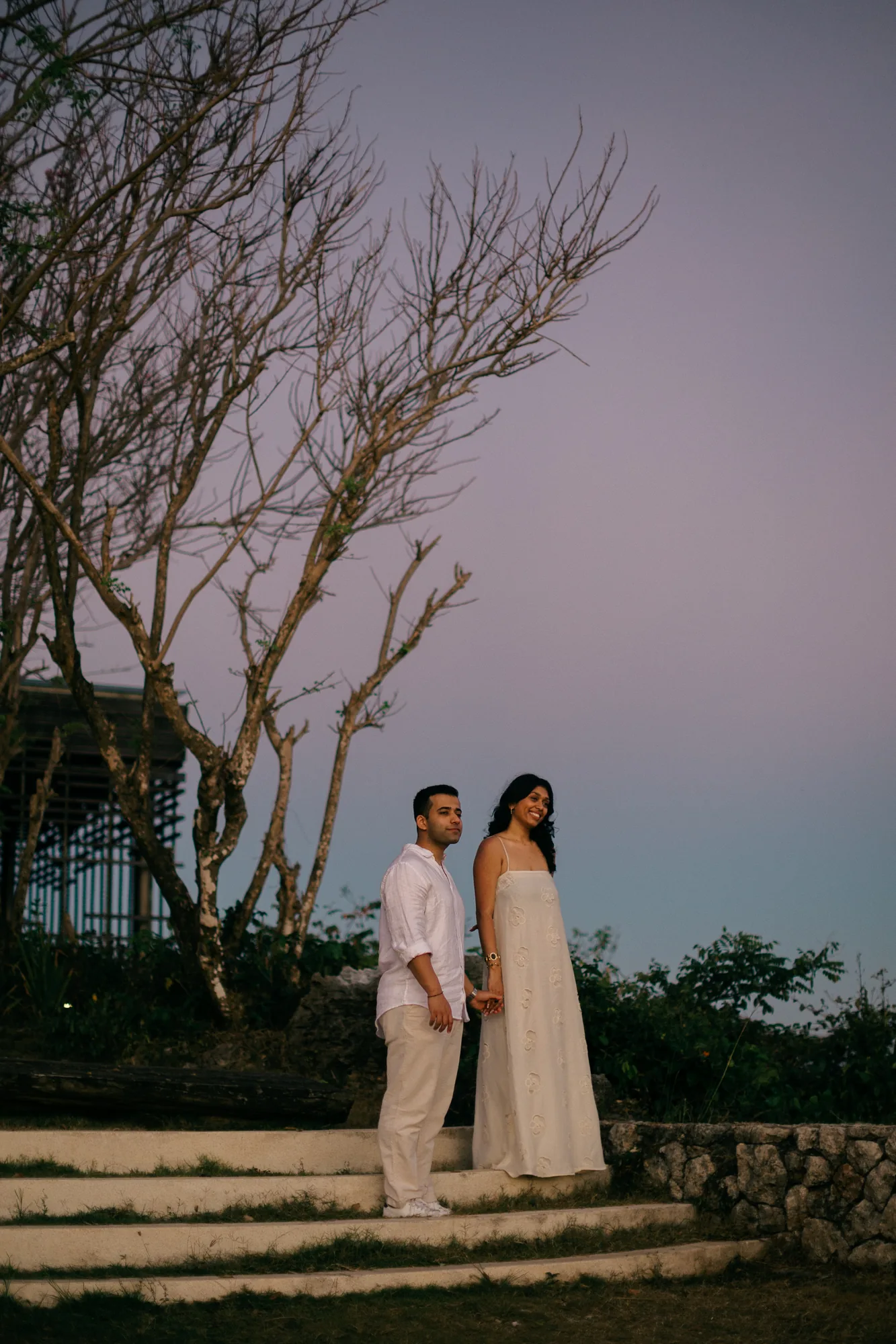 Couple portrait at dusk beside the trees at their Bali cliff proposal