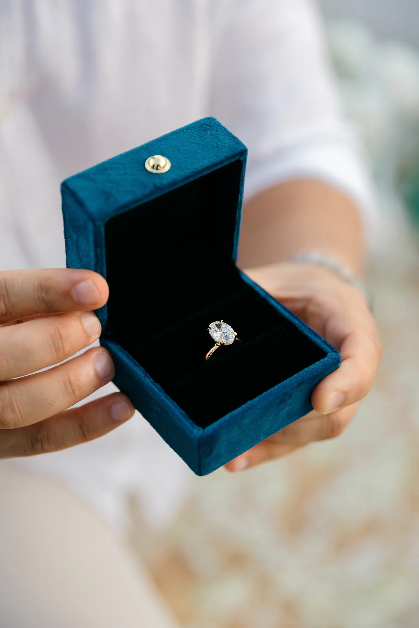 Hand holding an open ring box with a diamond engagement ring at a Bali proposal