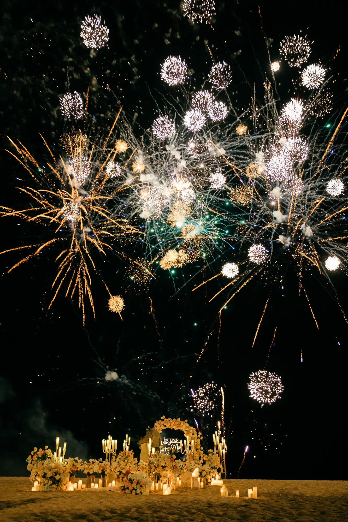 Golden fireworks over a beach floral proposal setup in Bali