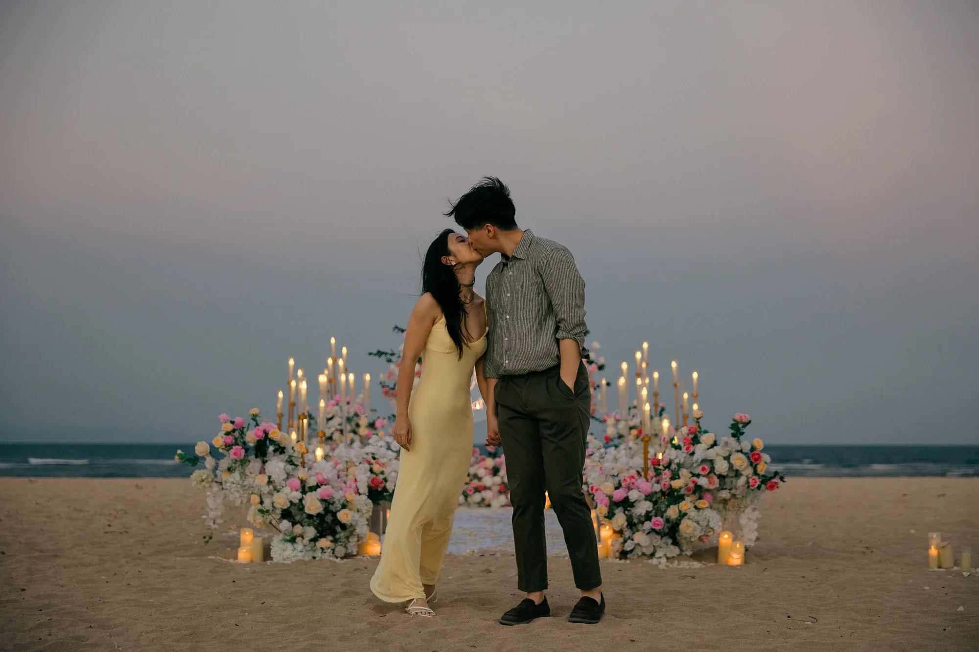 Couple kissing at their floral arch on the beach during a Bali proposal