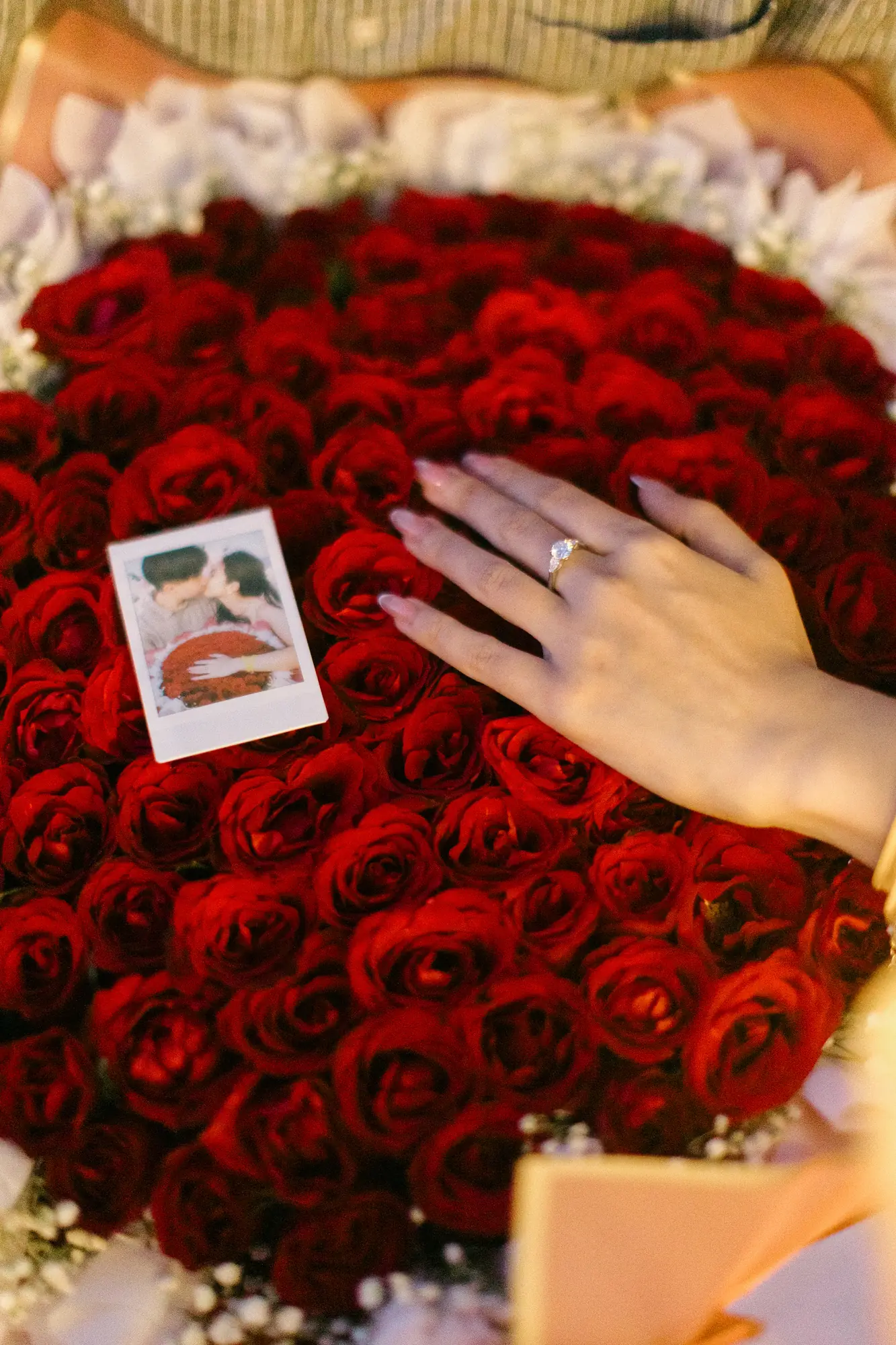 Engagement ring on her hand resting on a bouquet of red roses at a Bali proposal