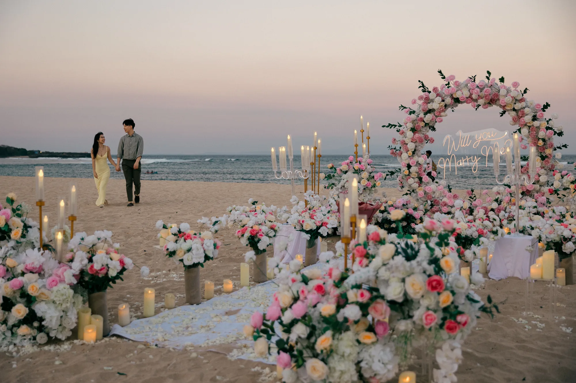 Pink and white floral proposal arch set up on the beach in Bali