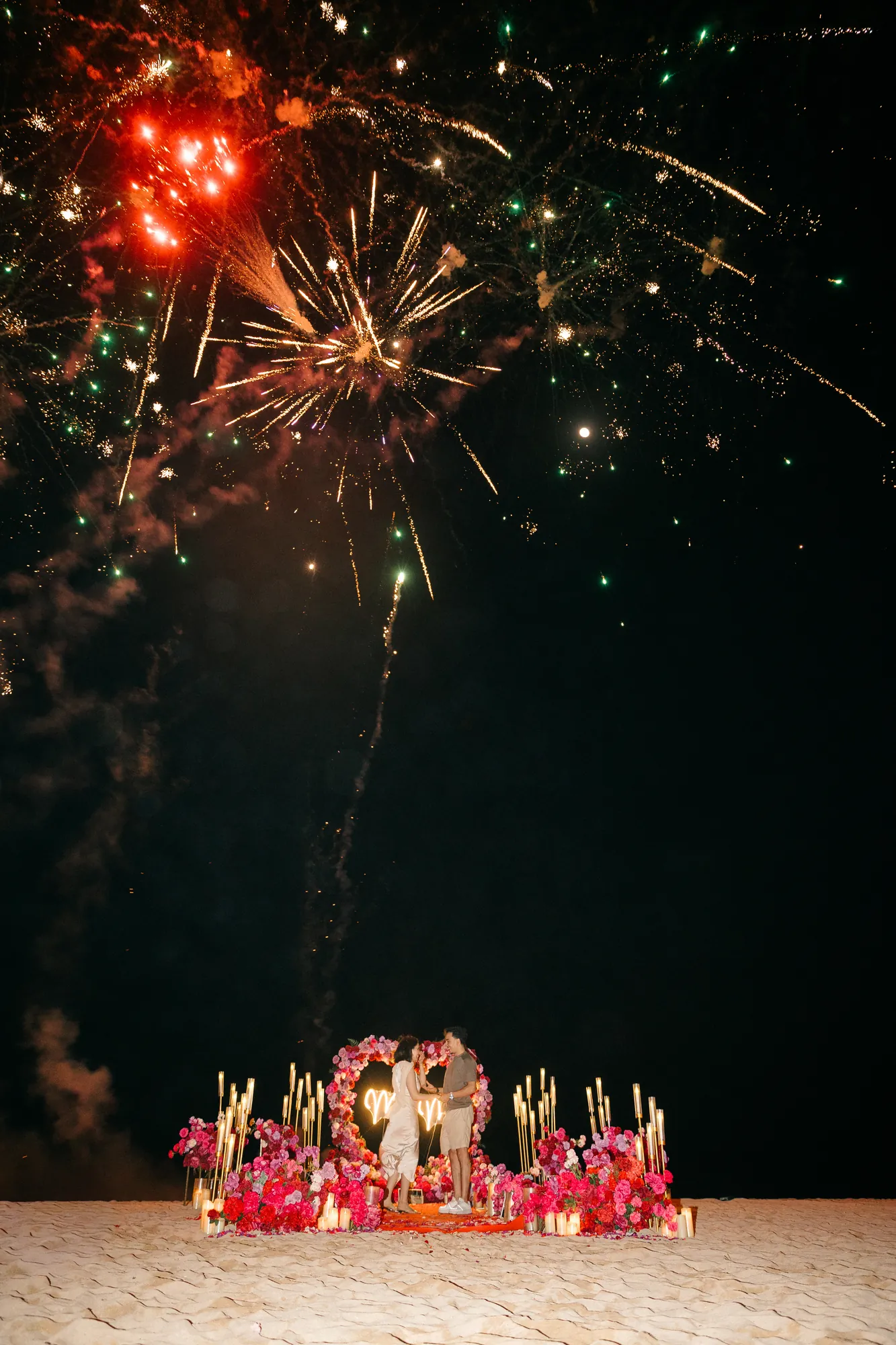 Red firework burst over a beach proposal setup in Bali