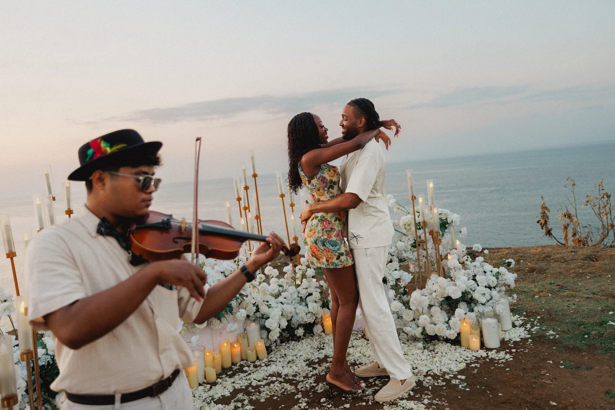 Couple embracing as a violinist plays above the ocean in Bali