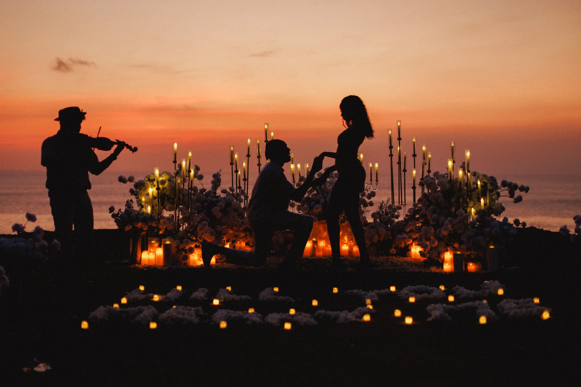 Violinist and couple in silhouette at sunset on a Bali clifftop