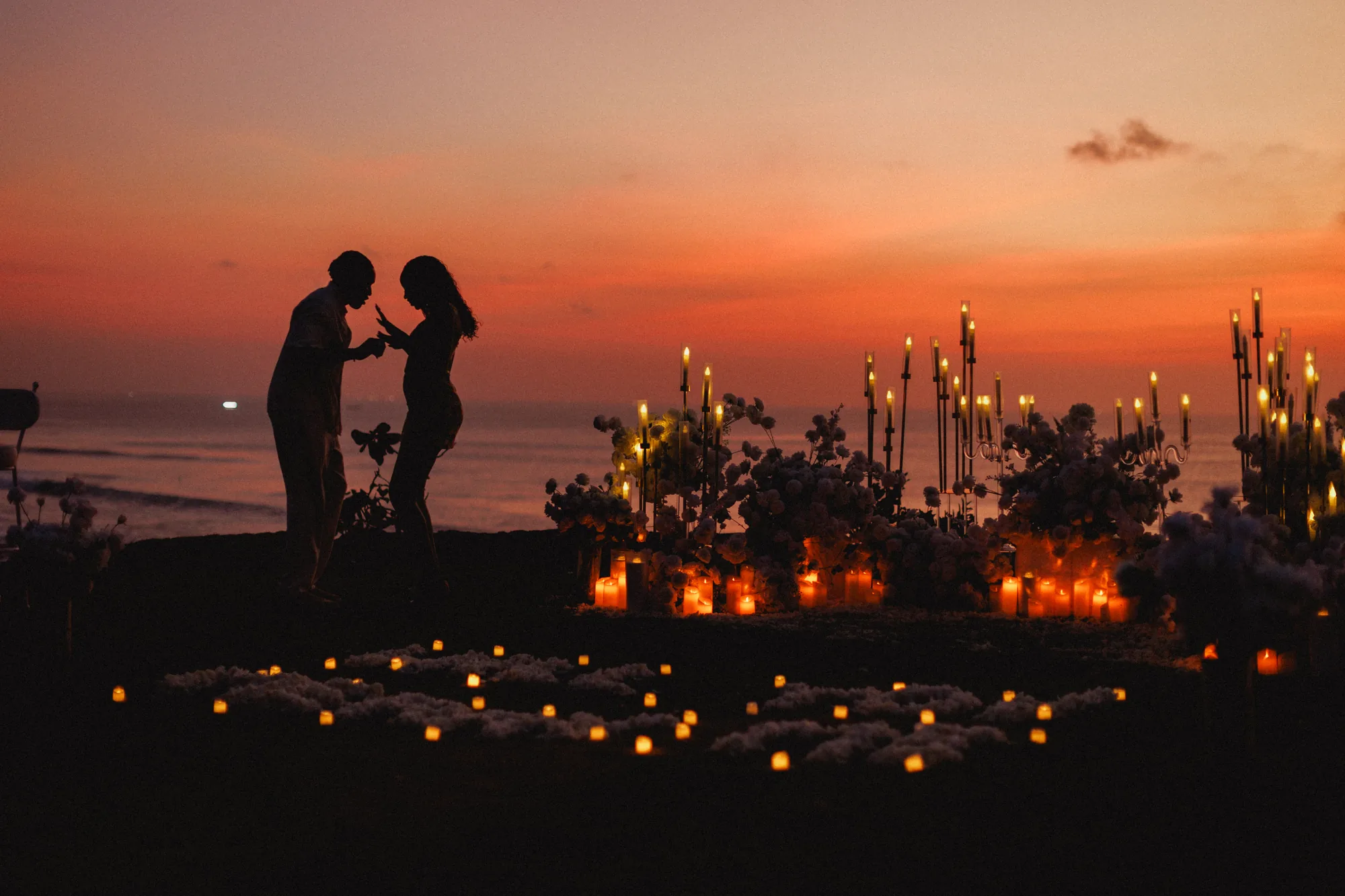 Couple silhouette against the sunset at a Bali cliff proposal
