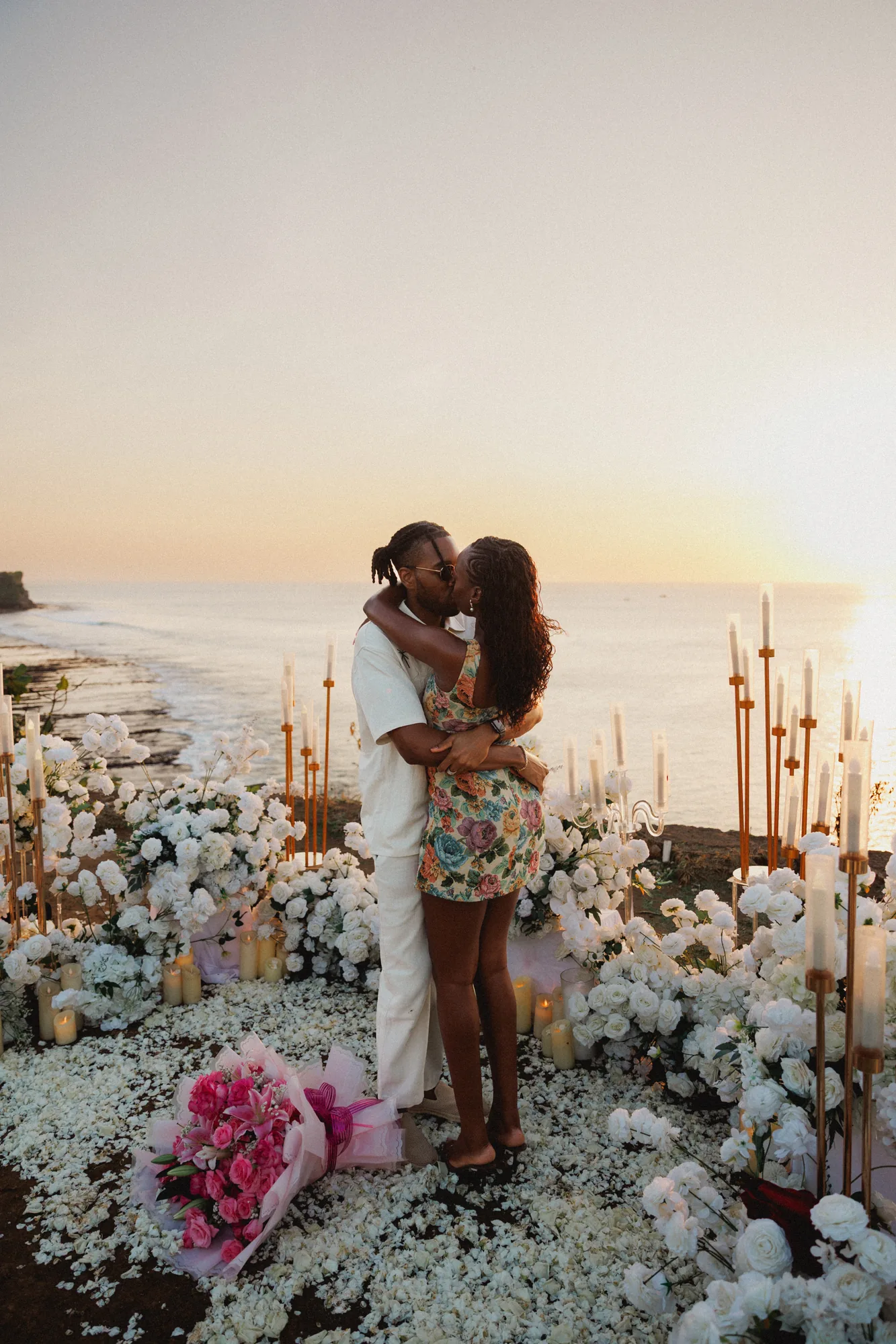 Couple embracing among white florals at a Balangan cliff proposal in Bali