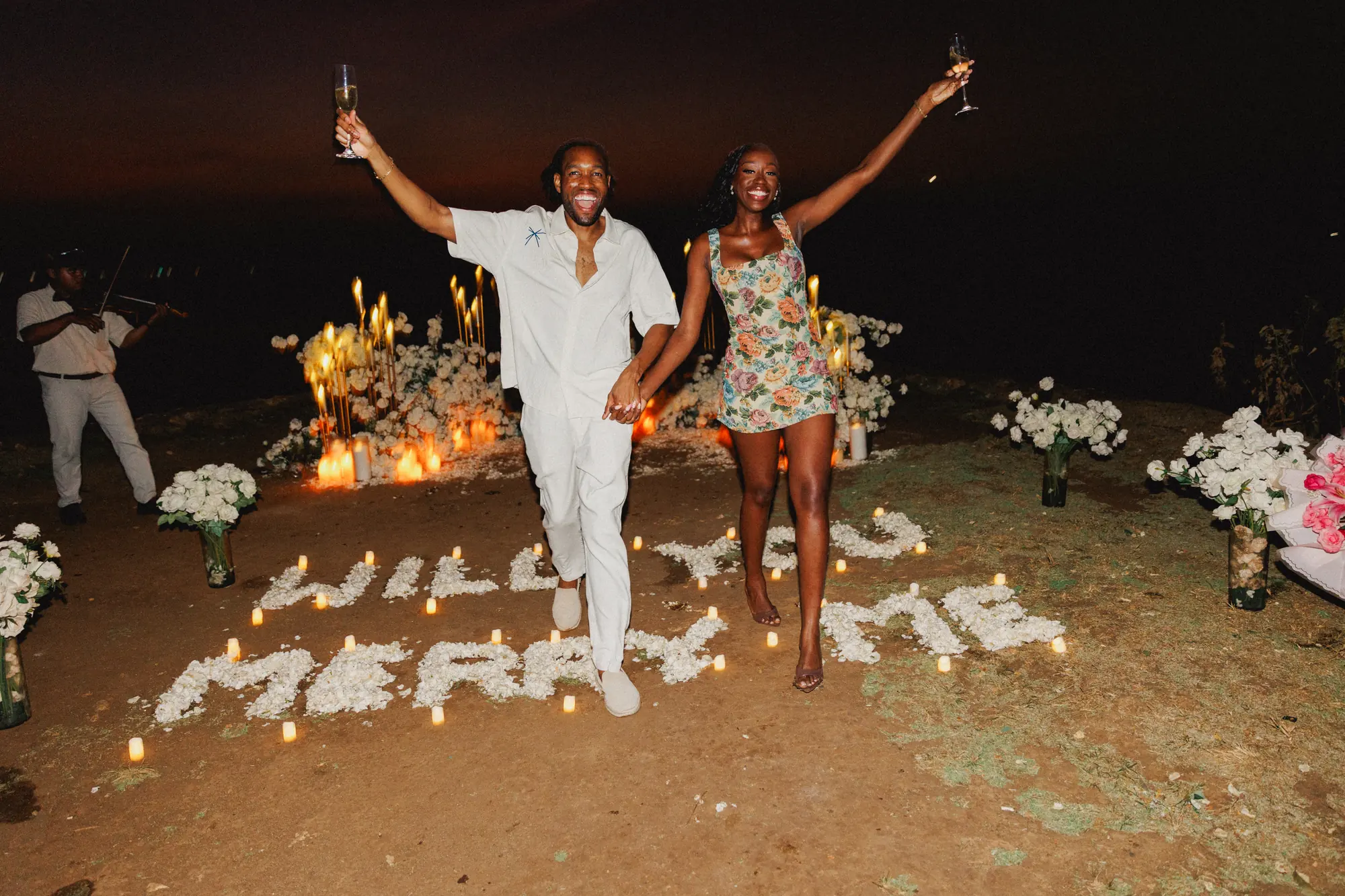 Couple celebrating at a Will You Marry Me candle sign in Bali
