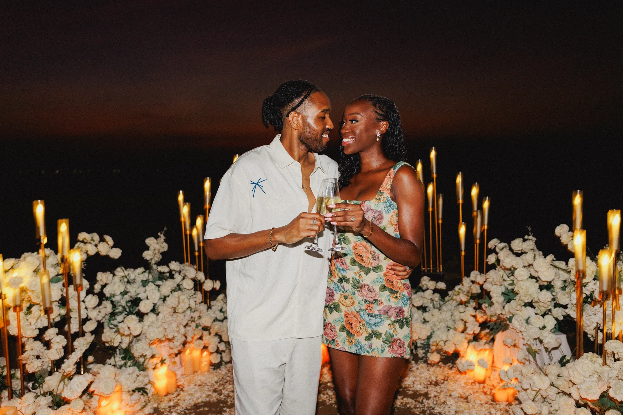 Couple kissing with champagne at a candlelit Bali proposal